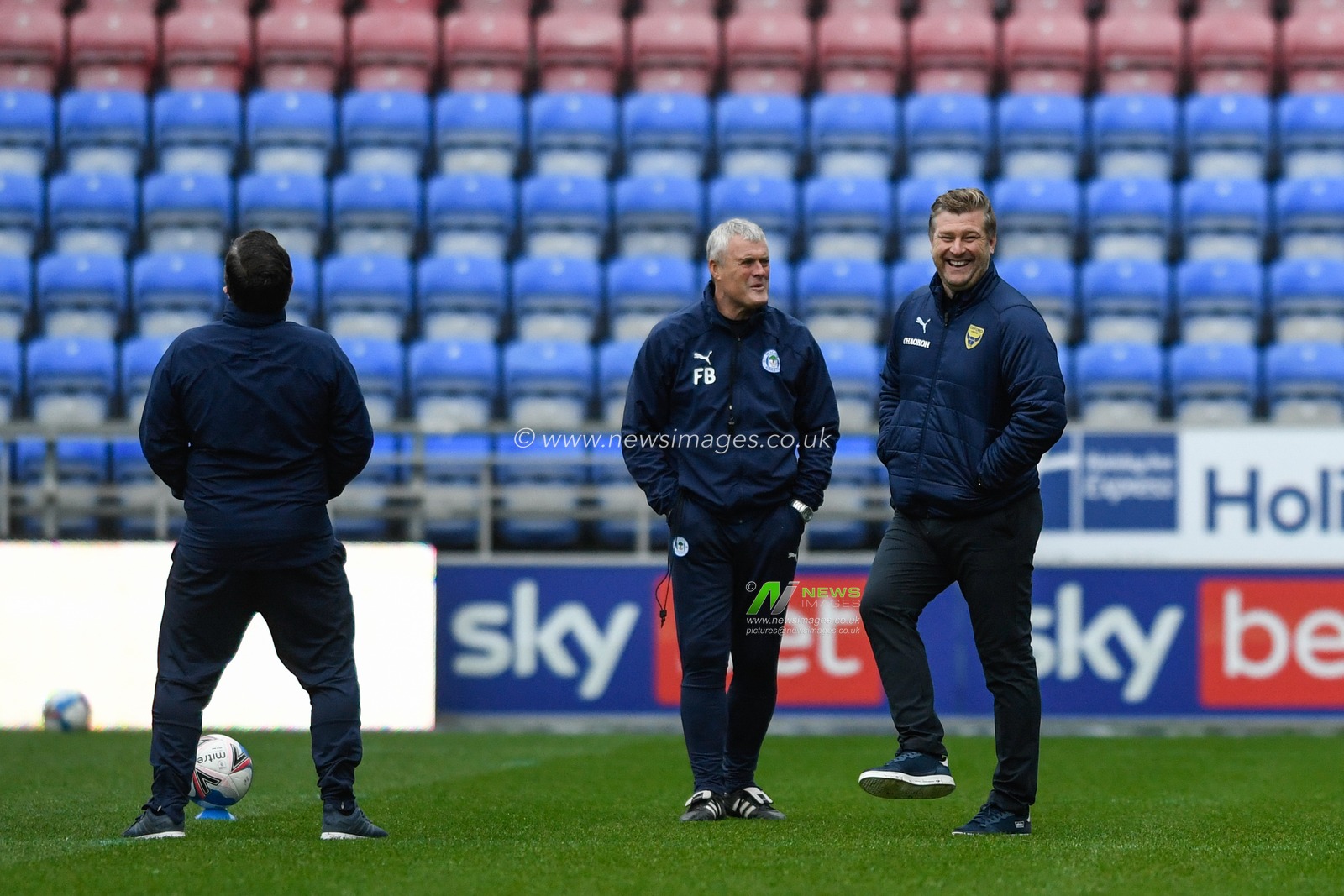 Karl Robinson manager of Oxford United shares a joke with some of the Wigan Athletic staff before the game