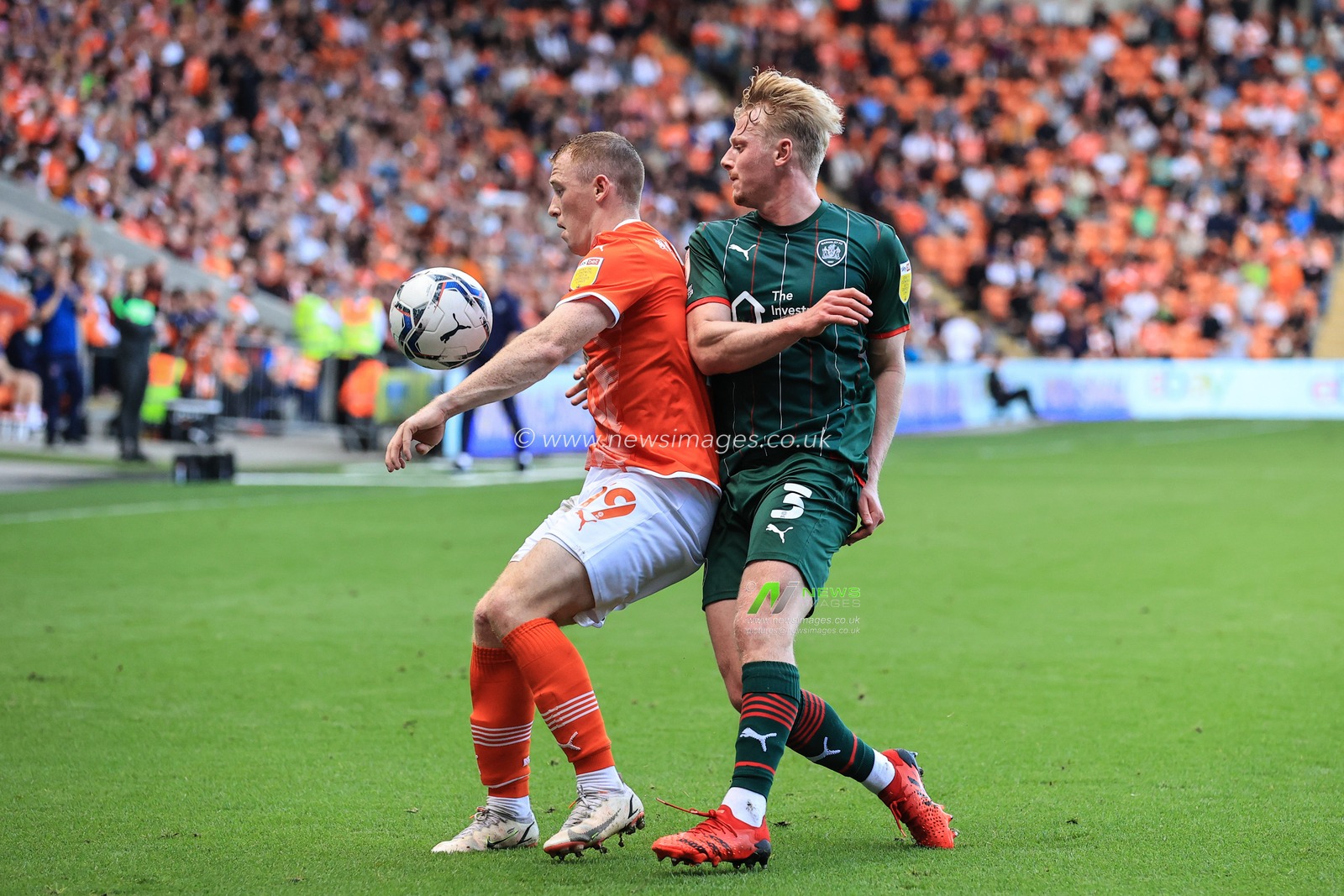 Shayne Lavery #19 of Blackpool holds the ball under pressure from Ben Williams #3 of Barnsley
