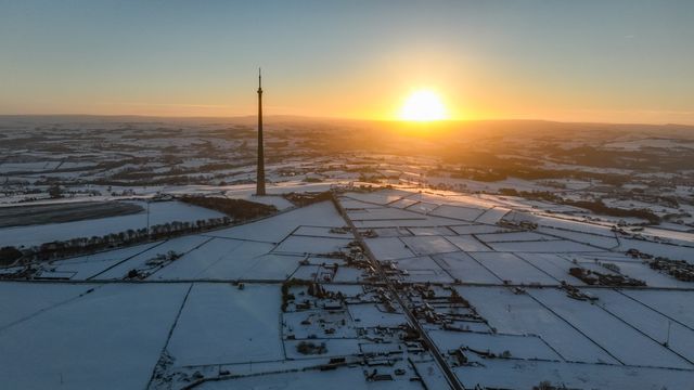 The sun sets over Emley Moor transmitting tower and the snow covered village of Emley as Sub-zero temperatures continue to hamper the north of the United Kingdom; Emley, Huddersfield, United Kingdom, 10th January 2025

(Photo by Mark Cosgrove/News Images)