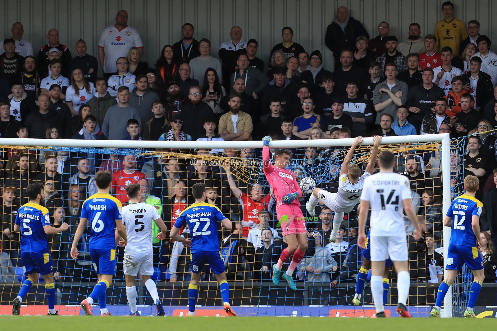 Nik Tzanev #1 of AFC Wimbledon sees a ball over the bar with Harry Darling #6 of Milton Keynes Dons close by.