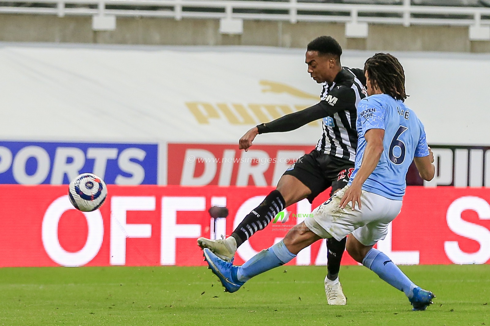 Joe Willock #28 of Newcastle United shoots at goal whilst under pressure from Nathan AkÃ© #6 of Manchester City