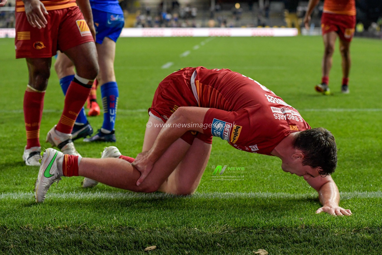 Matt Whitley (11) of Catalans Dragons holds his leg in pain after scoring a try