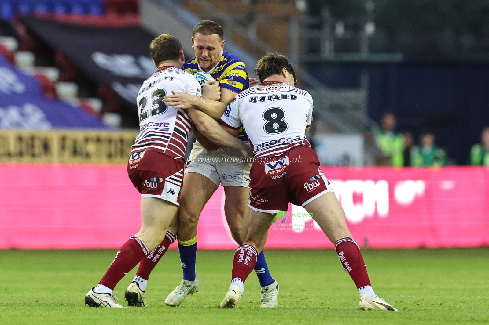 Ben Currie of Warrington Wolves is tackled by Kian McDermott of Wigan Warriors and Ethan Havard of Wigan Warriors during the Betfred Super League round 18 match Wigan Warriors vs Warrington Wolves at The Brick Community Stadium, Wigan, United Kingdom on 10 July 2026

(Photo by Mark Cosgrove/News Images)