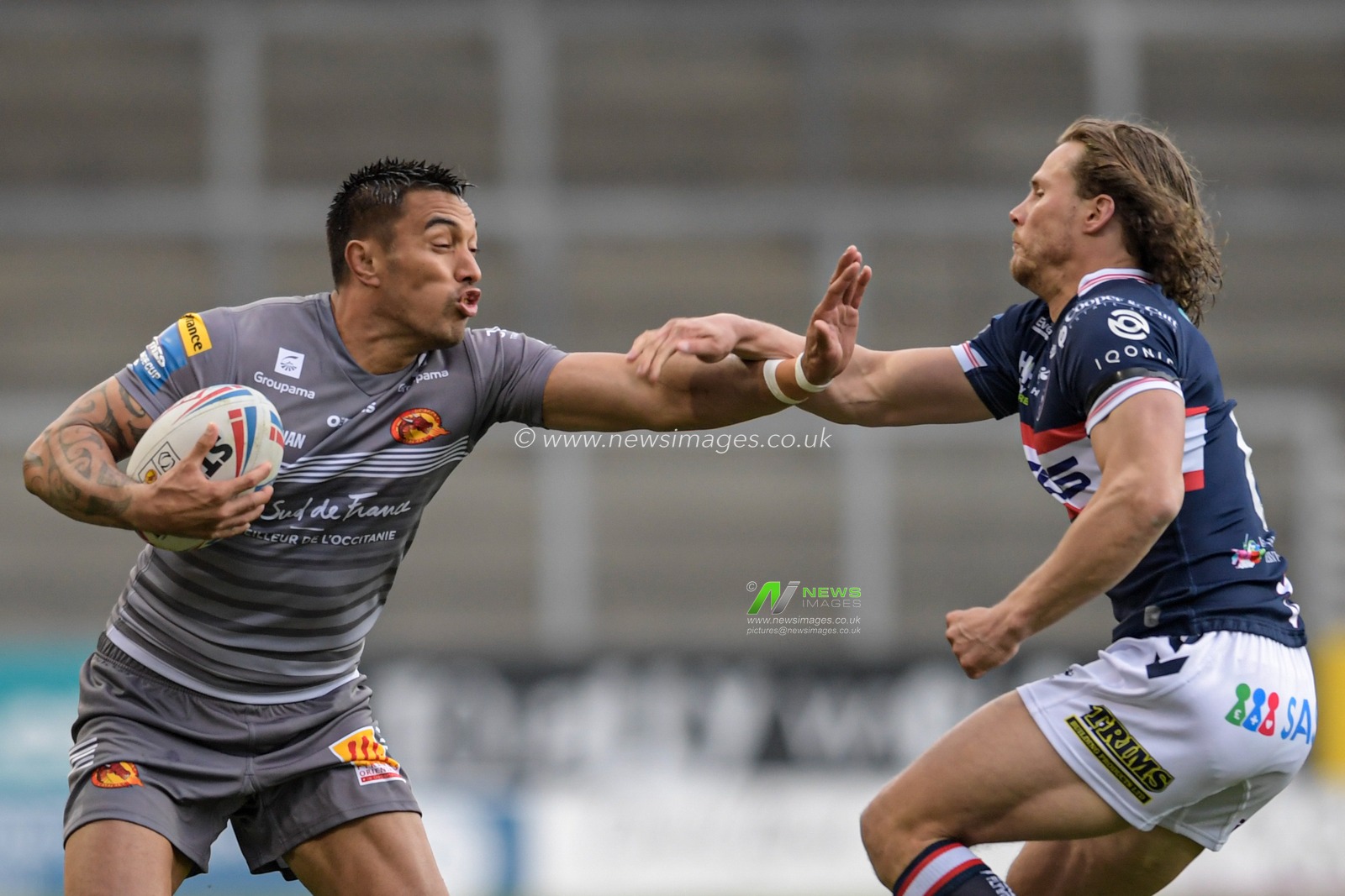 Dean Whare (4) of Catalans Dragons holds off the tackle attempt from Jacob Miller (6) of Wakefield Trinity