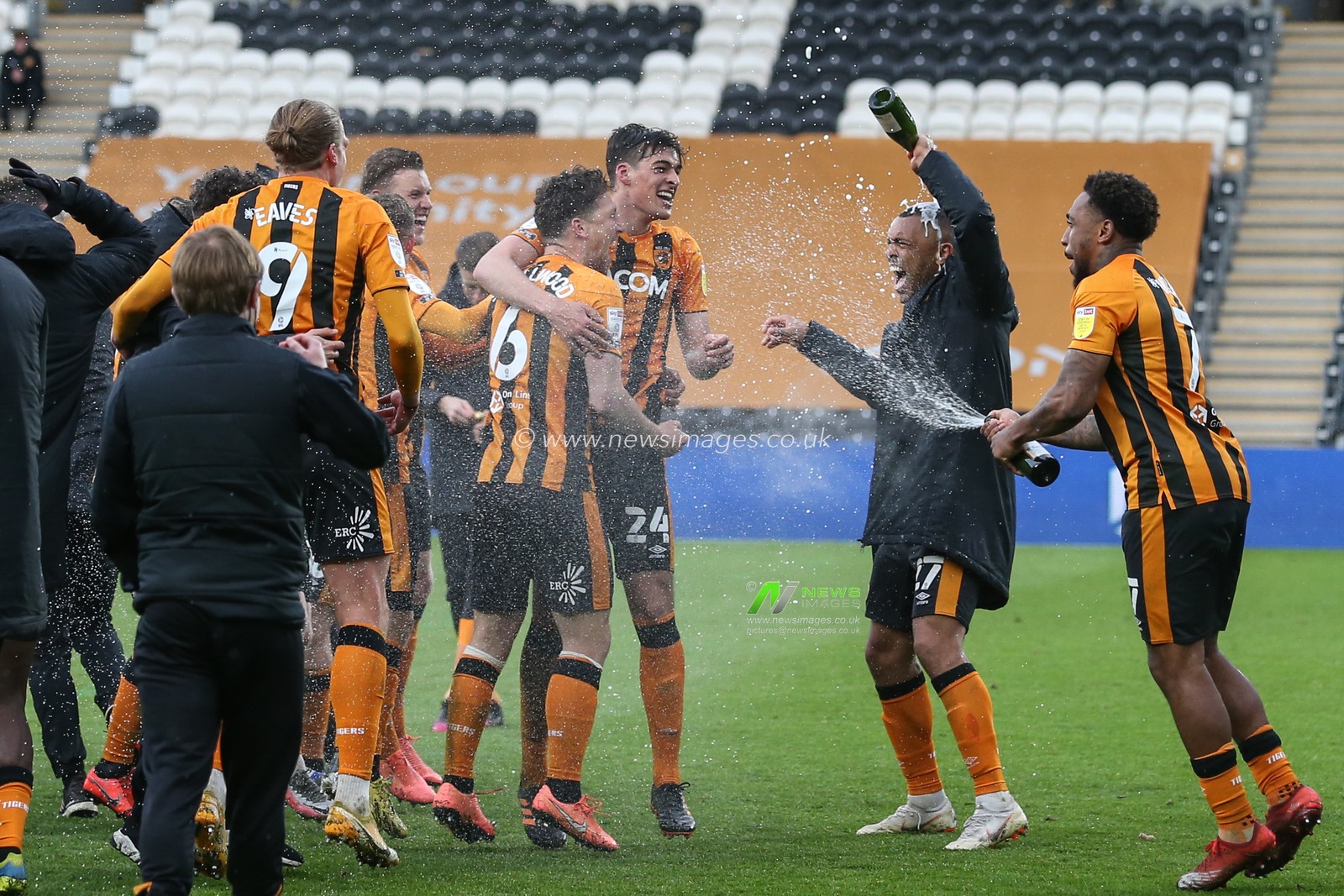 Hull City players celebrate on the pitch after the final whistle with champagne after being told they were Division one champions