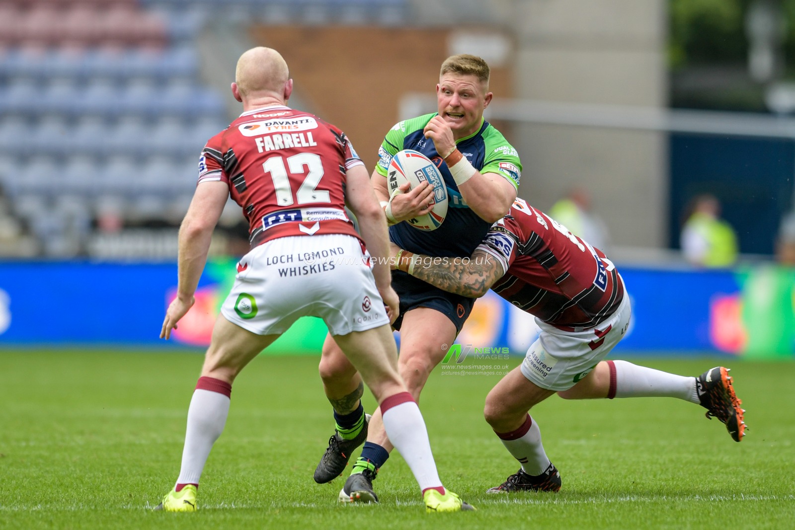 Luke Yates (8) of Huddersfield Giants is tackled by Brad Singleton (8) of Wigan Warriors and Liam Farrell (12) of Wigan Warriors