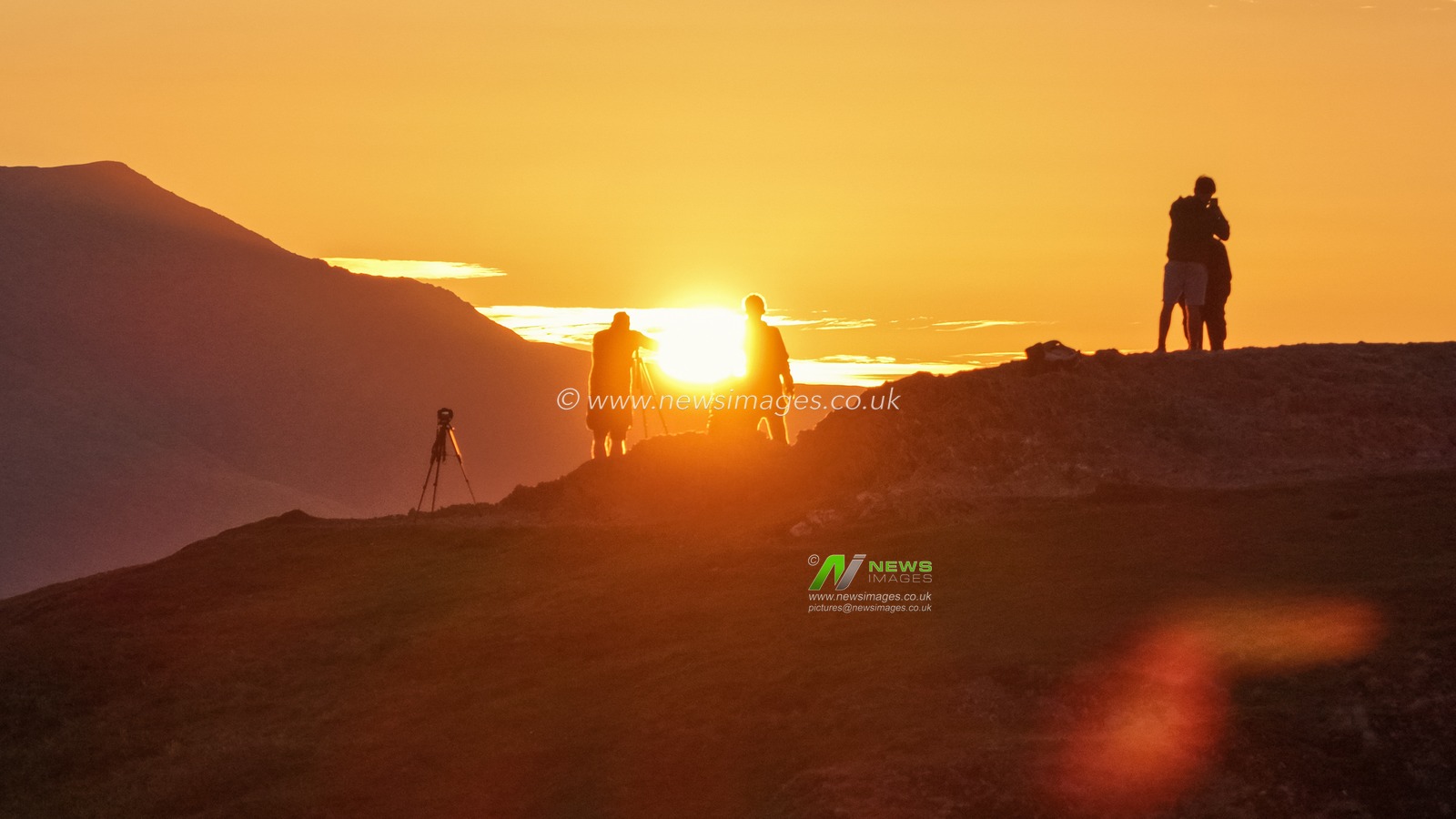 Photographers take pictures as the sun rises from the summit of Catbells overlooking Derwent Water and the town of Keswick In the Lake District, Cumbria, United Kingdom, 19th June 2025

(Photo by Mark Cosgrove/News Images)