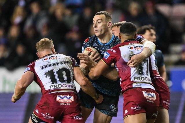 Frankie Halton of Leigh Leopards is tackled by Luke Thompson and ï»¿ï»¿ï»¿Kruise Leeming of Wigan Warriors during the Betfred Super League Round 1 match Wigan Warriors vs Leigh Leopards at The Brick Community Stadium, Wigan, United Kingdom, 13th February 2025

(Photo by Craig Thomas/News Images)
