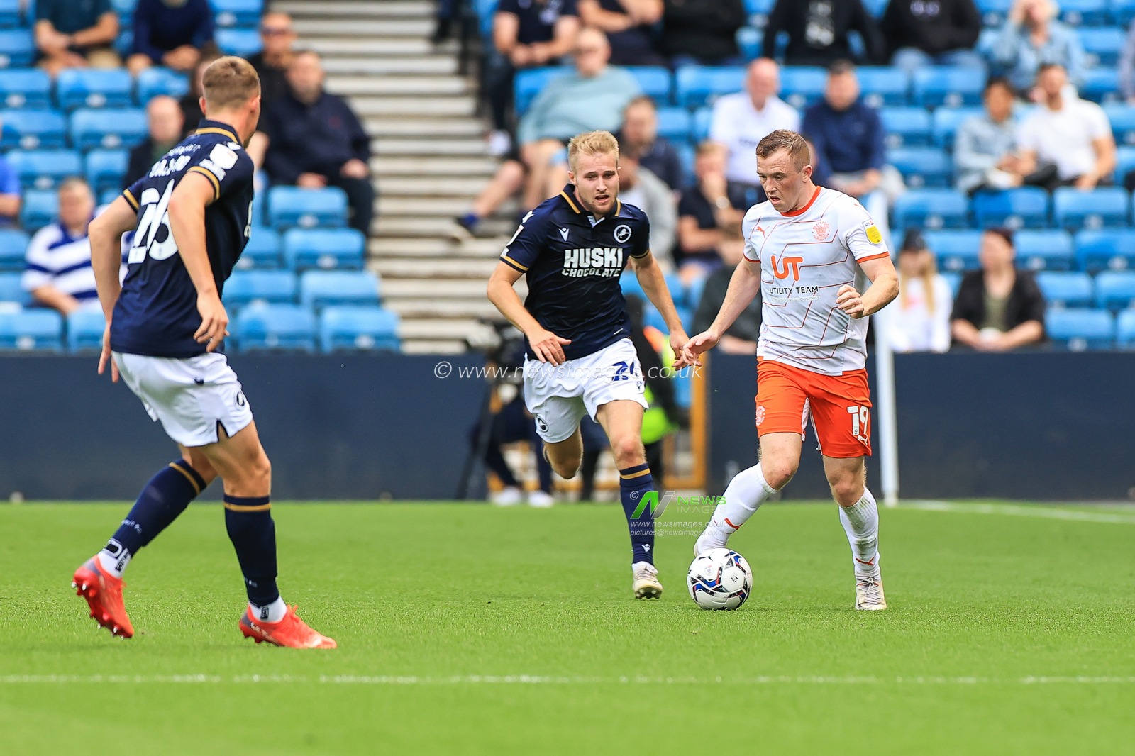 Shayne Lavery #19 of Blackpool makes a break with the ball  despite the pressure from Billy Mitchell #24 of Millwall