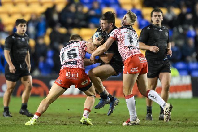 Adam Holroyd of Warrington Wolves is tackled by Matty Davis and Brad Dwyer of Leigh Leopards during the Toby King's Testimonial match Warrington Wolves vs Leigh Leopards at Halliwell Jones Stadium, Warrington, United Kingdom, 1st February 2025

(Photo by Craig Thomas/News Images)