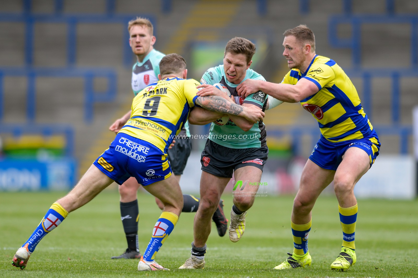 Matt Parcell (9) of Hull KR is tackled by Ben Currie (11) of Warrington Wolves and Daryl Clark (9) of Warrington Wolves
