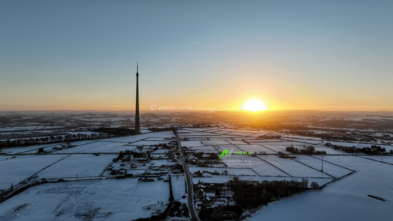 The sun sets over Emley Moor transmitting tower and the snow covered village of Emley as Sub-zero temperatures continue to hamper the north of the United Kingdom; Emley, Huddersfield, United Kingdom, 10th January 2025

(Photo by Mark Cosgrove/News Images)