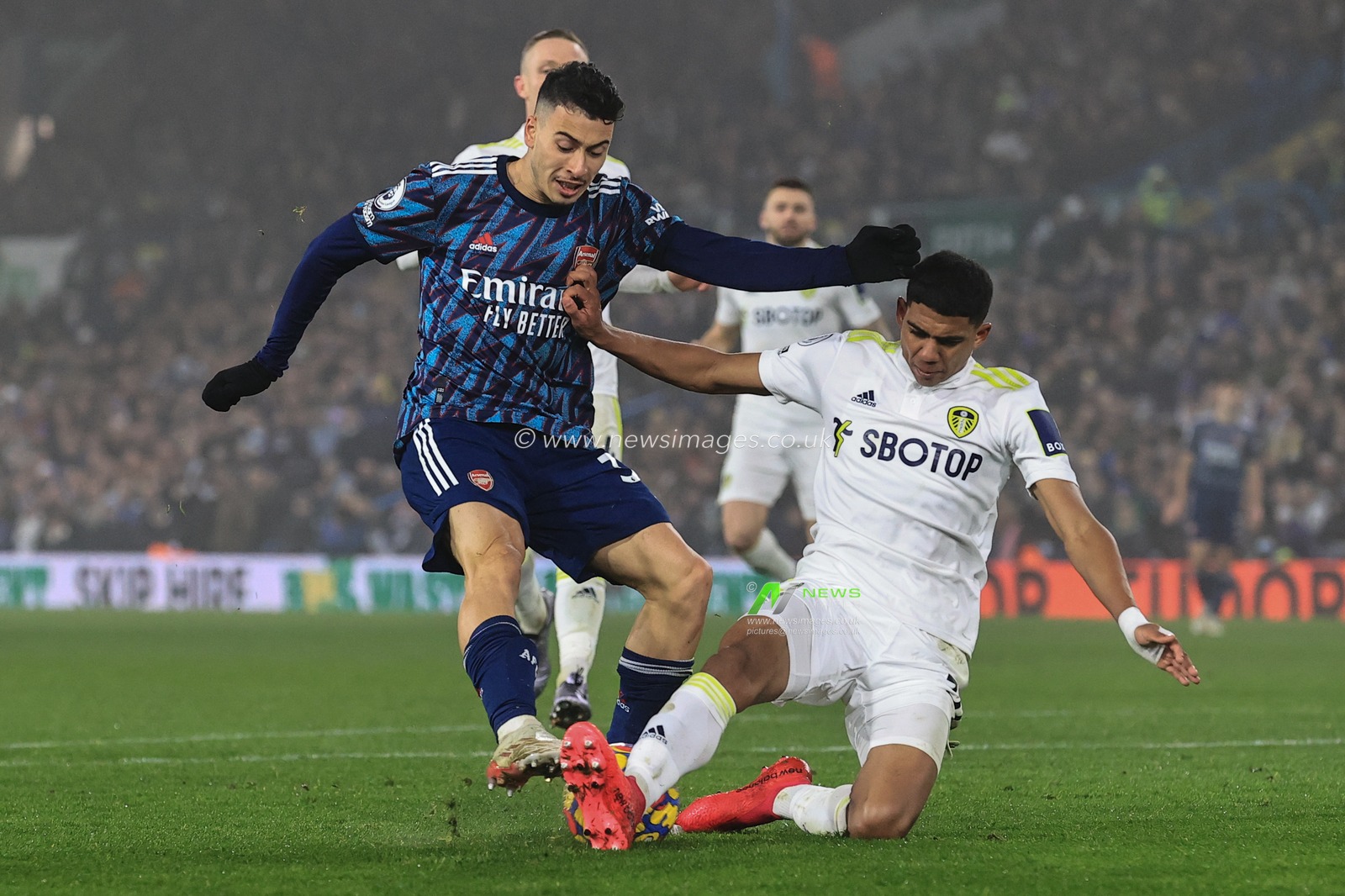 Cody Drameh #37 of Leeds United slides in to tackle Gabriel Martinelli #35 of Arsenal