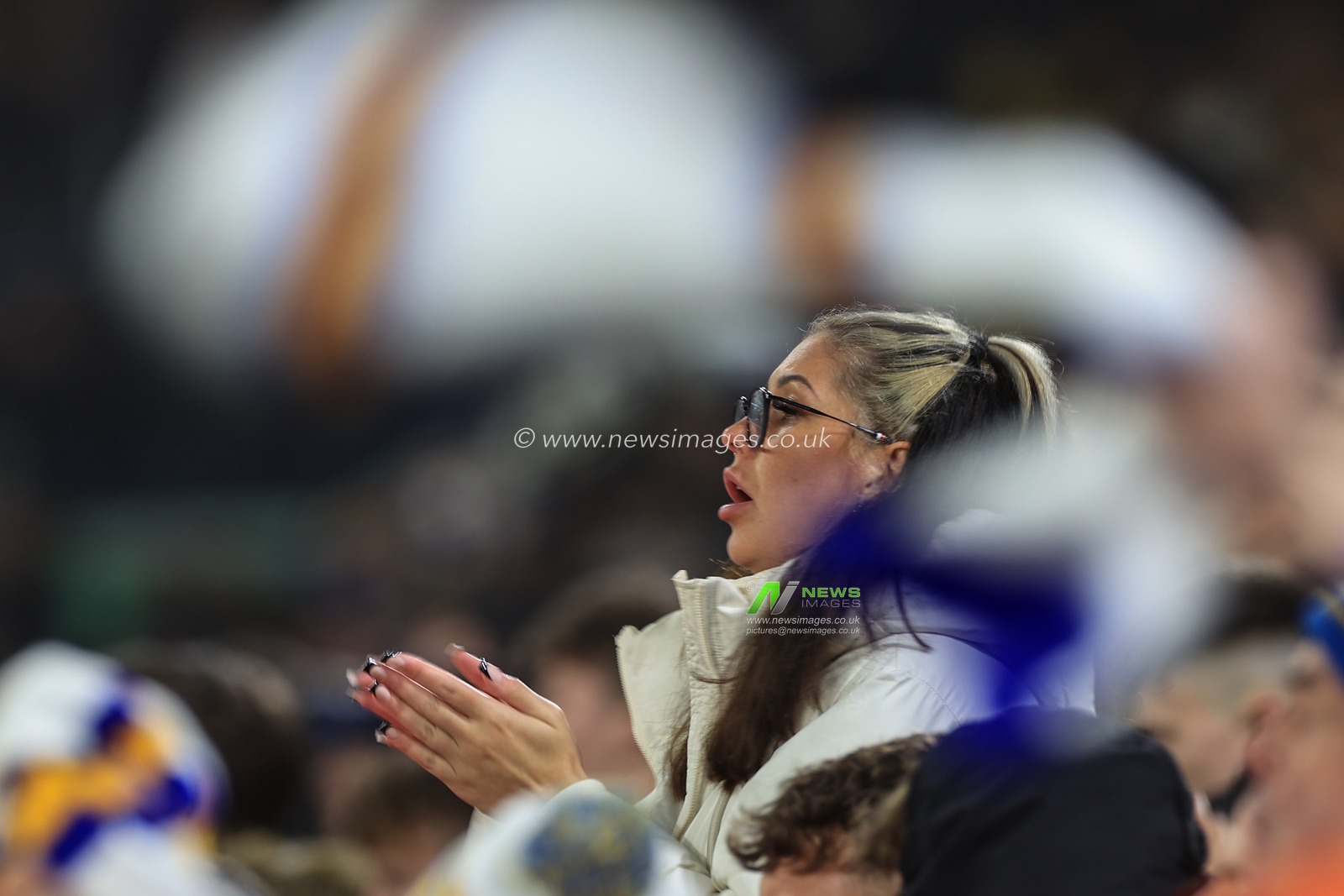 A Leeds fans claps and sings away under a sea of spinning  Leeds United scarfs