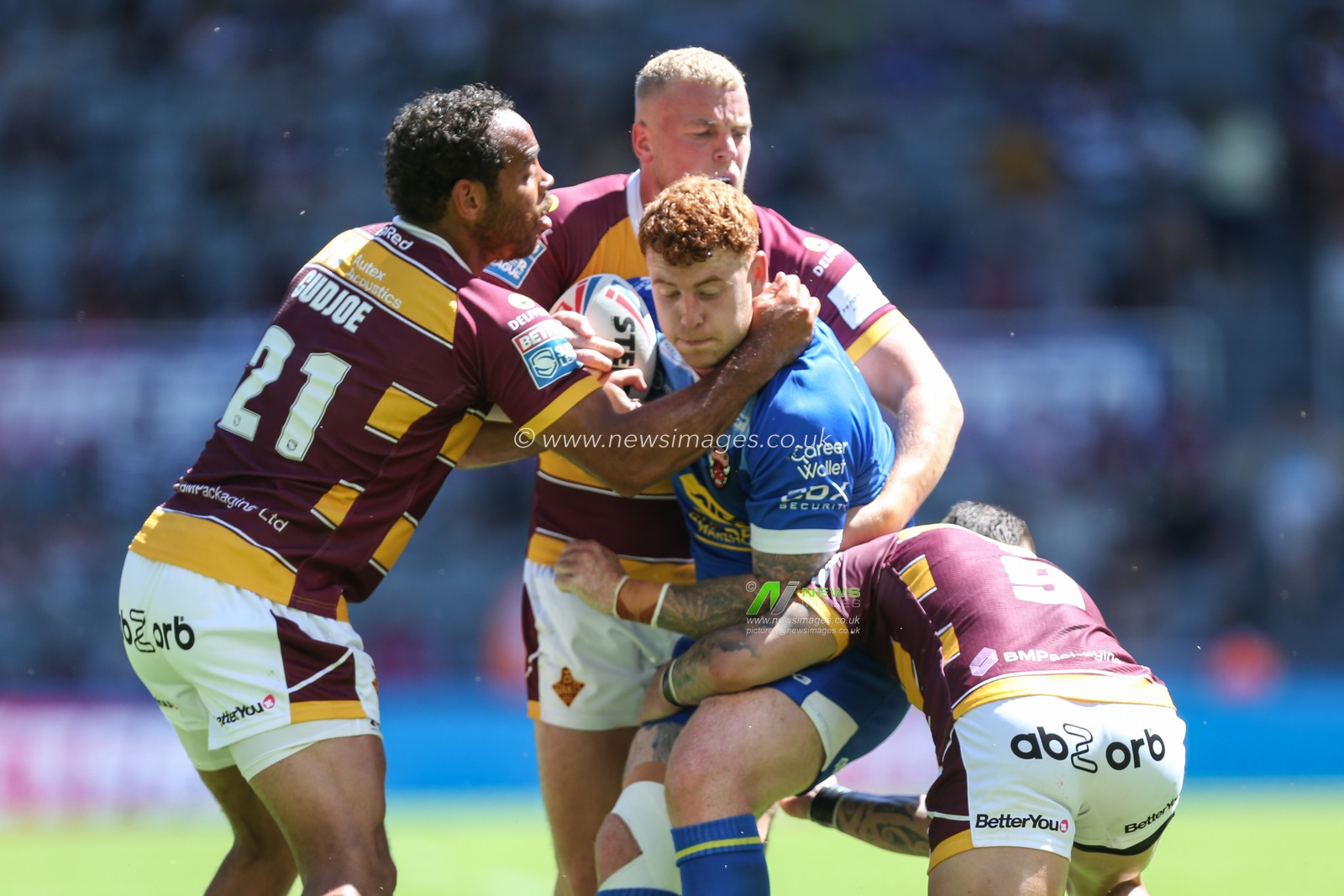 Harvey Livett #17 of Salford Red Devils is stopped by the Huddersfield defence