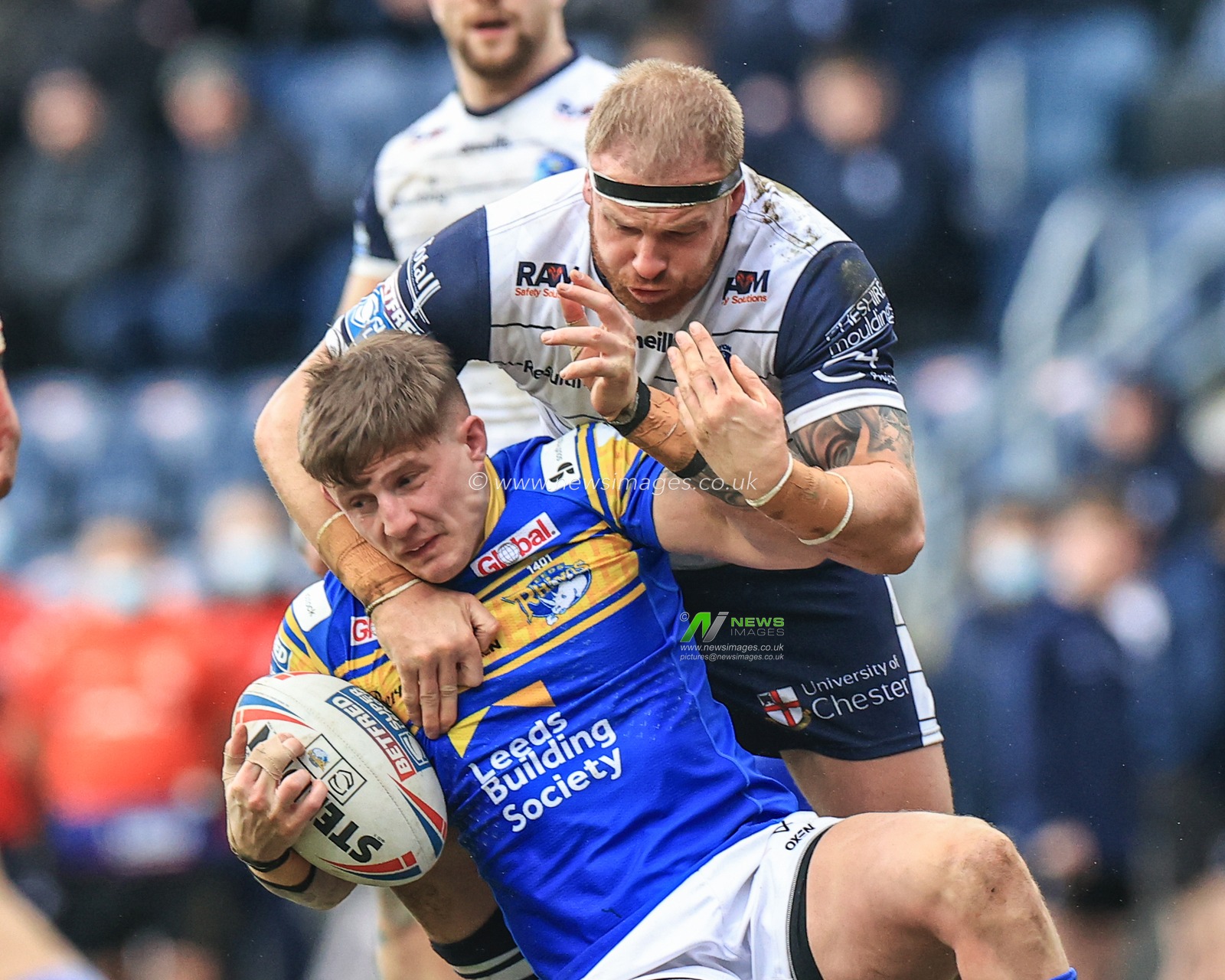 Liam Sutcliffe #4 of Leeds Rhinos is tackled by Oliver Holmes #12 of Warrington Wolves