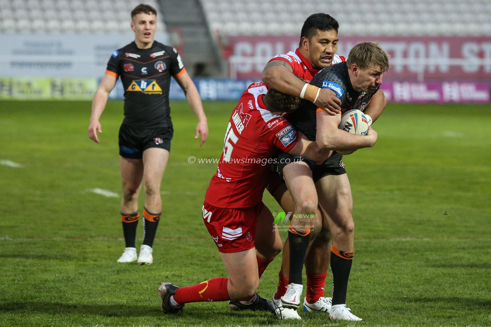 Michael Shenton (4) of Castleford Tigers is tackled by Albert Vete (8) and George Lawler (15) of Hull KR
