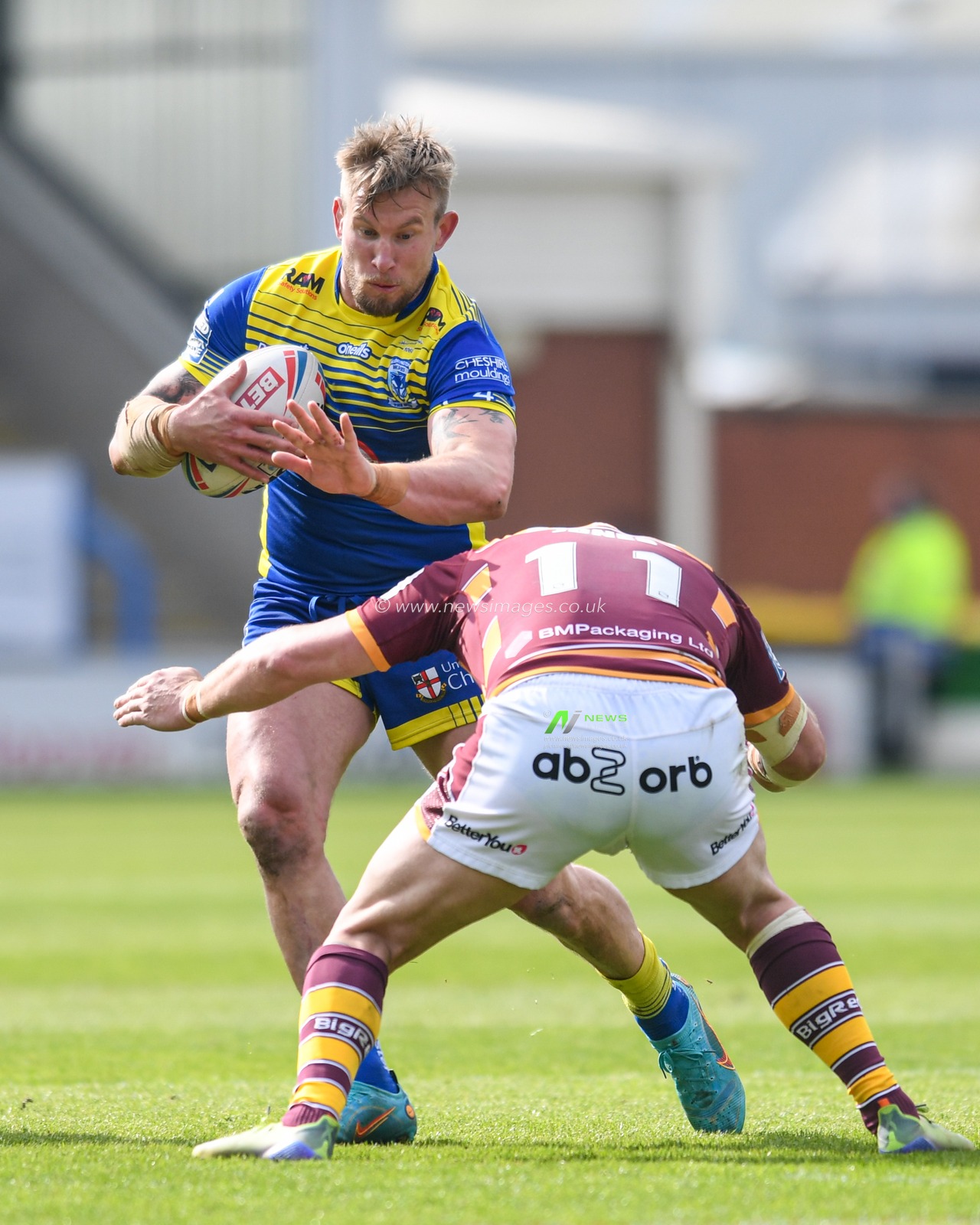 Mike Cooper #10 of Warrington Wolves looks for a way past Josh Jones #11 of Huddersfield Giants