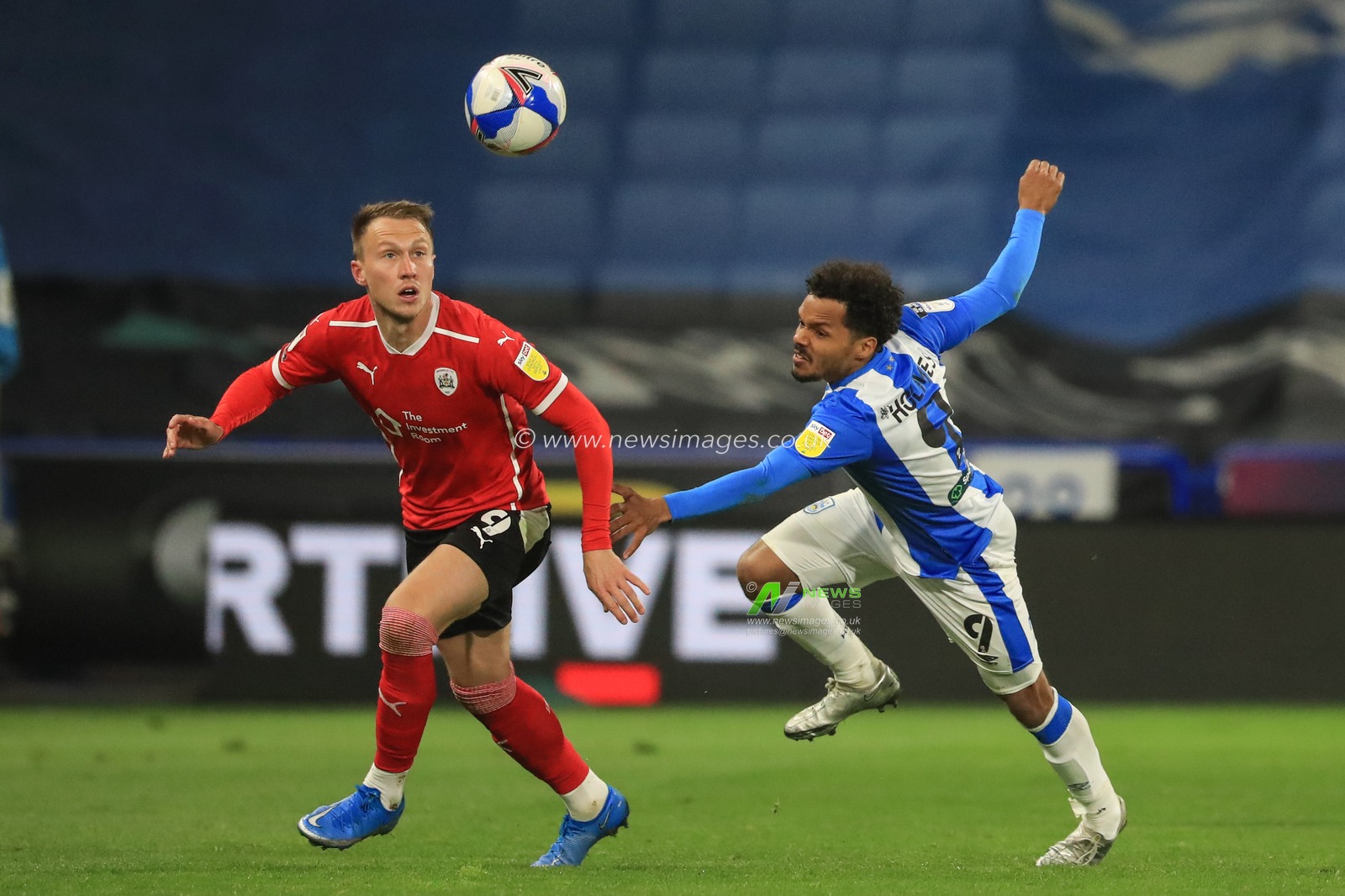 Cauley Woodrow #9 of Barnsley chases the ball as Duane Holmes #9 of Huddersfield Town tracks him