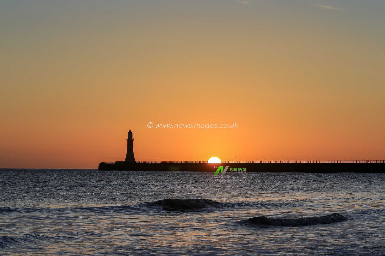 The sun begins to peek over Roker Pier and Lighthouse in Sunderland at sunrise