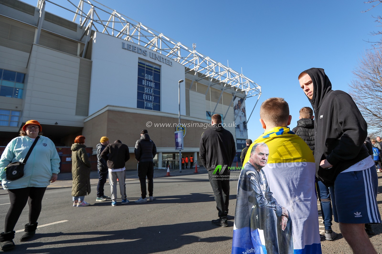 A young Leeds United supporter stands outside Elland Road Stadium wearing a Marcelo Bielsa flag as the manager was sacked by the club this morning