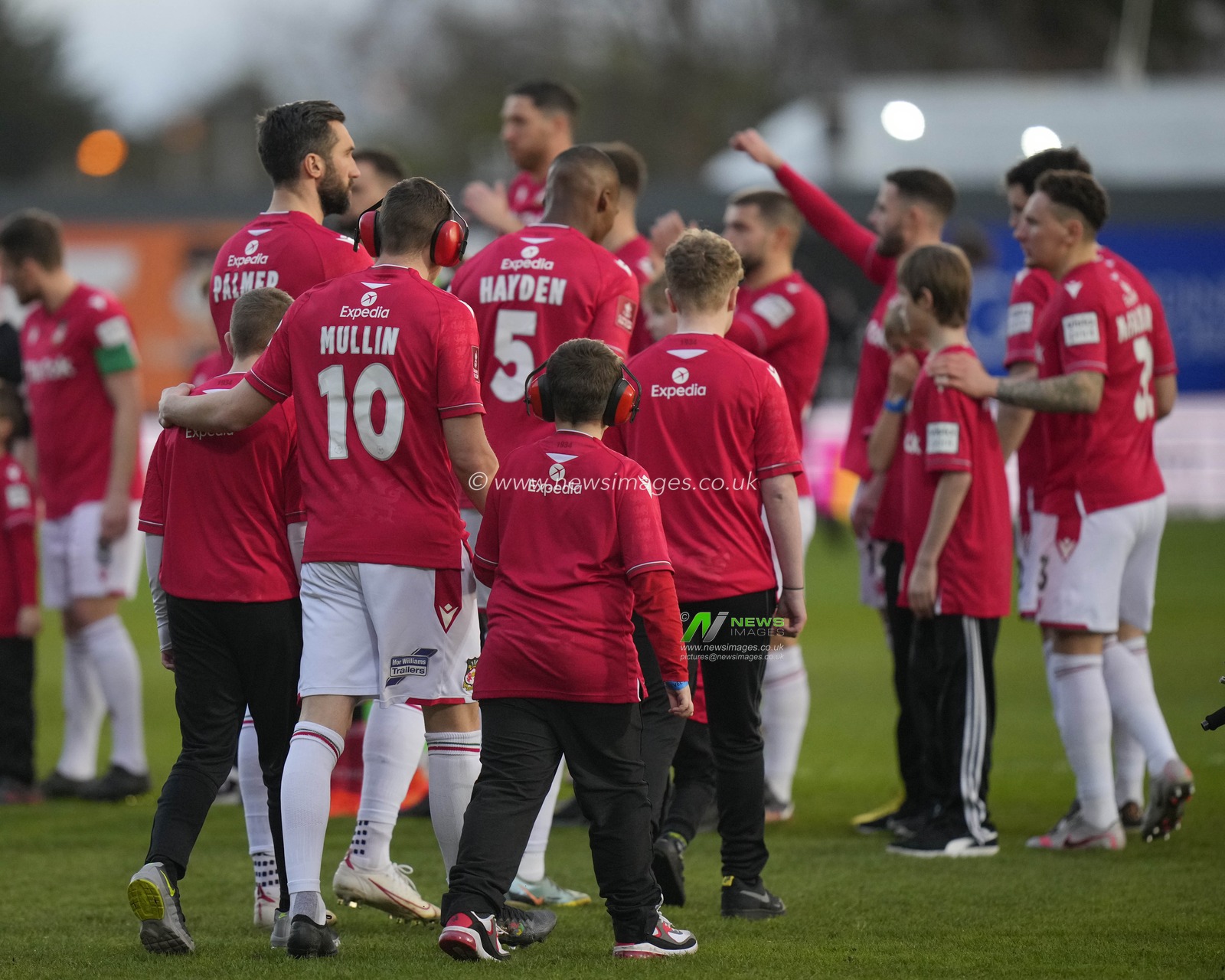 Paul Mullin #10 of Wrexham wears ear defenders like those worn by the young mascot he walks out with before the Emirates FA Cup fourth round match Wrexham vs Sheffield United at The Racecourse Ground, Wrexham, United Kingdom, 29th January 2023

(Photo by Steve Flynn/News Images)