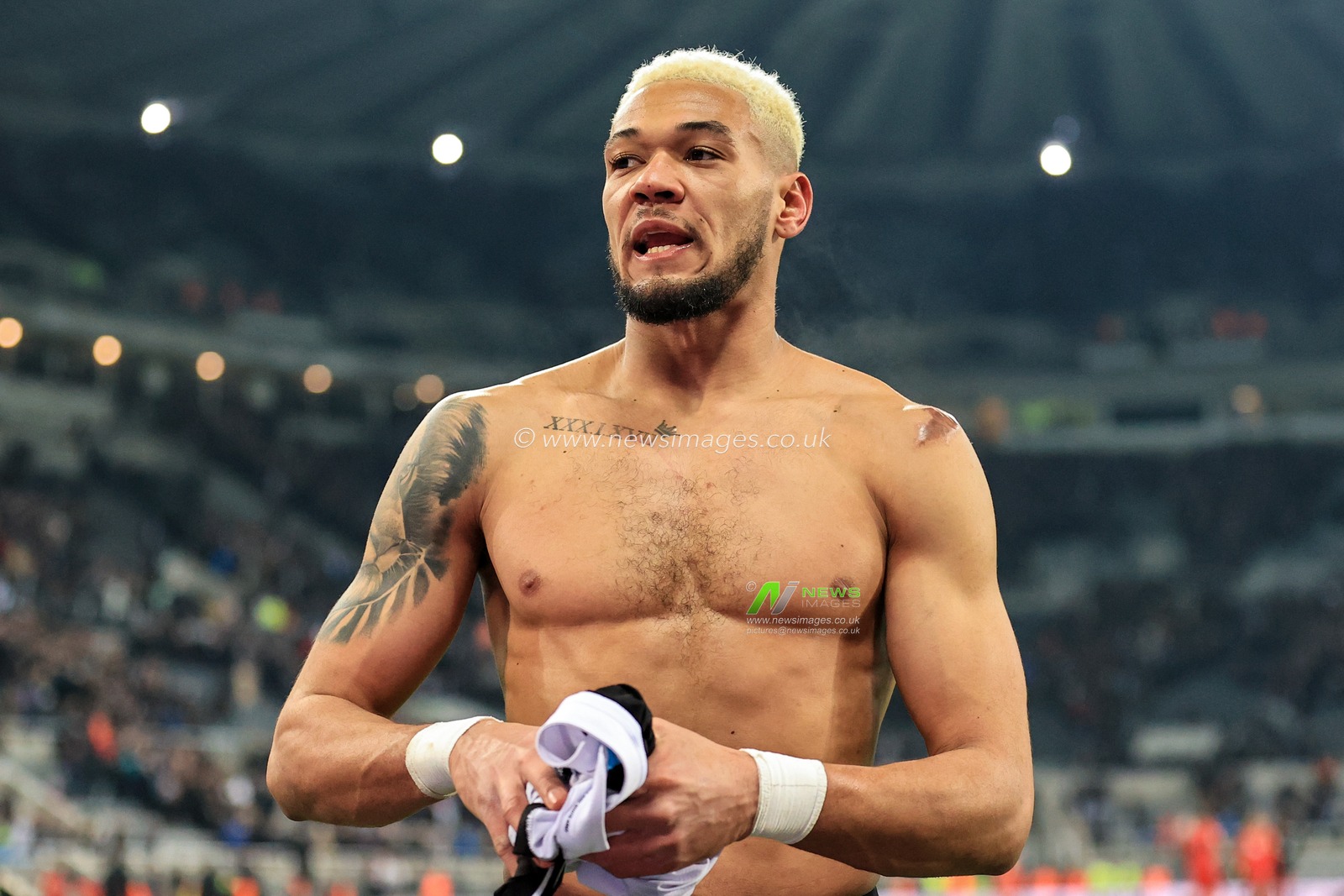 Joelinton #7 of Newcastle United takes off his shirt before giving it to a fan