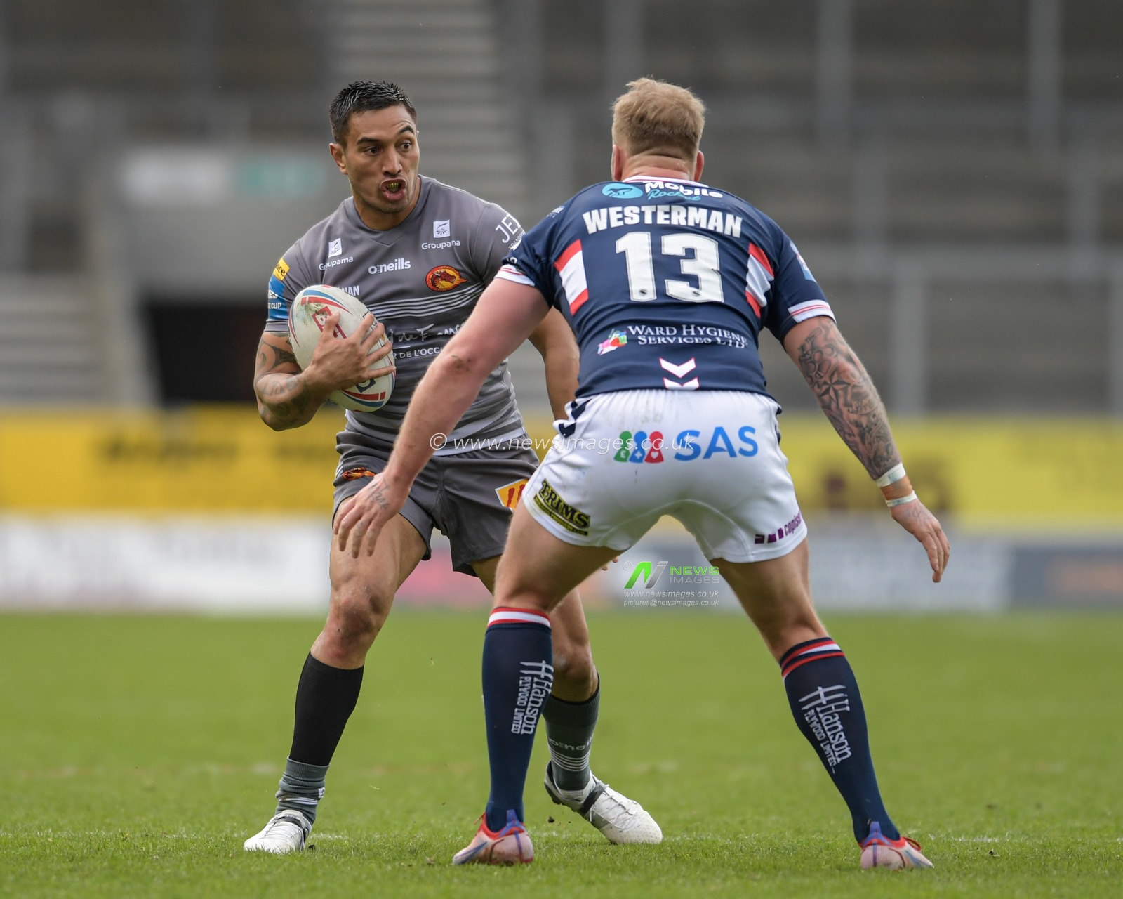 Dean Whare (4) of Catalans Dragons looks for a way past Joe Westerman (13) of Wakefield Trinity