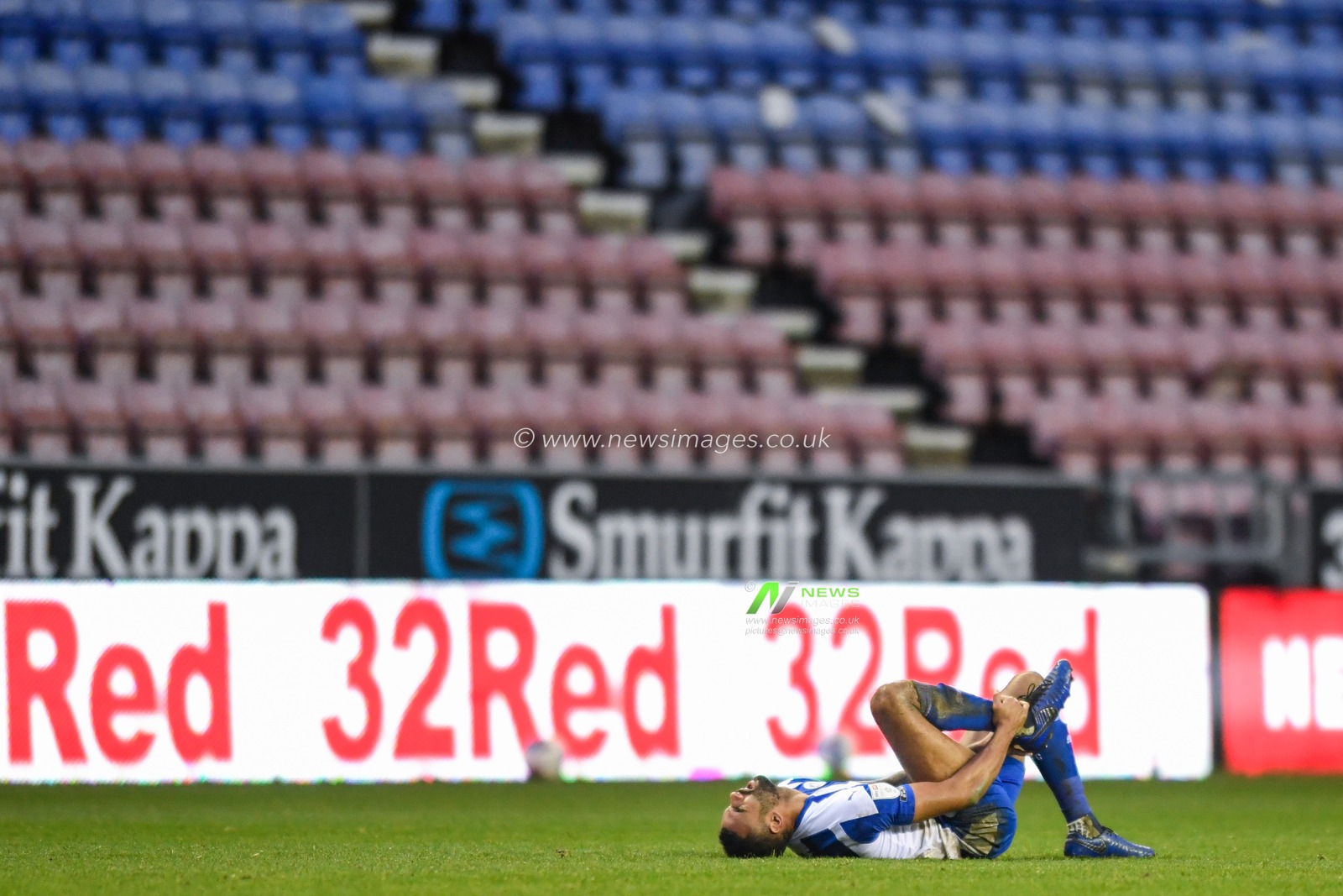 Curtis Tilt #4 of Wigan Athletic holds his ankle after an injury