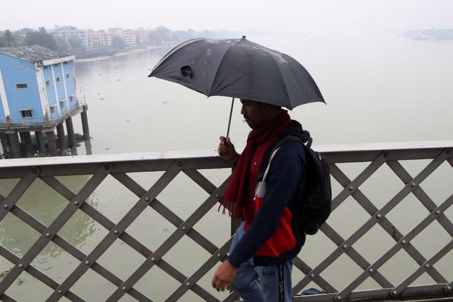 A man hold umbralla  walks through the Vivekananda Bridge over the Ganga River on a smoggy winter morning in Kolkata,India on 21 December 2024.Pictures by Debajyoti Chakraborty.(Photo: Debajyoti Chakraborty/News Images)