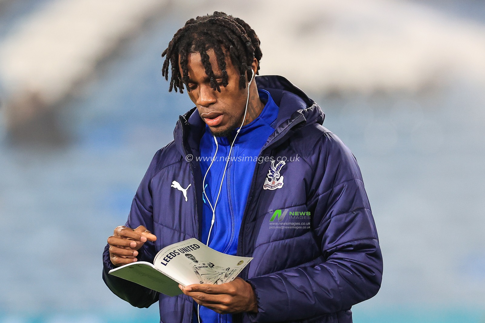 Wilfried Zaha #11 of Crystal Palace reads a match day programme