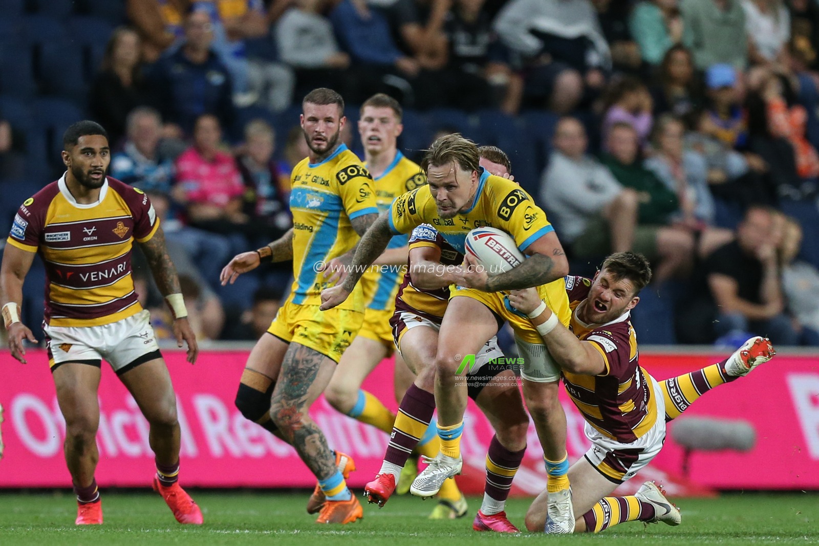 Blake Austin #6 of Leeds Rhinos gets through the Huddersfield defence