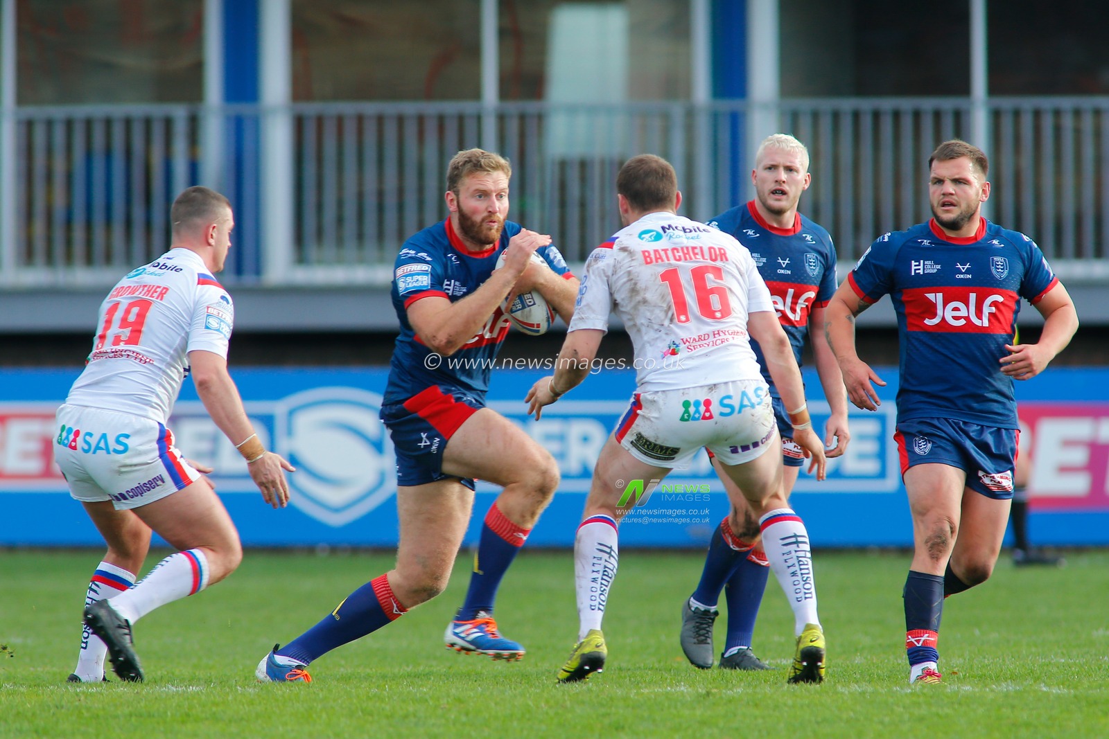 Will Maher (26) of Hull KR on the attack against Jordan Crowther (19) and James Batchelor (16) of Wakefield Trinity.