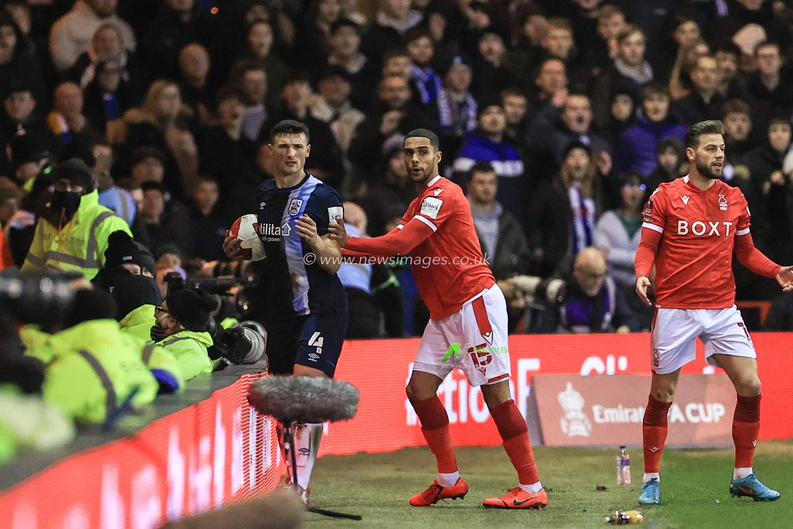 Max Lowe #15 of Nottingham Forest pushes Matty Pearson #4 of Huddersfield Town over the LED advertising board resulting in a yellow card