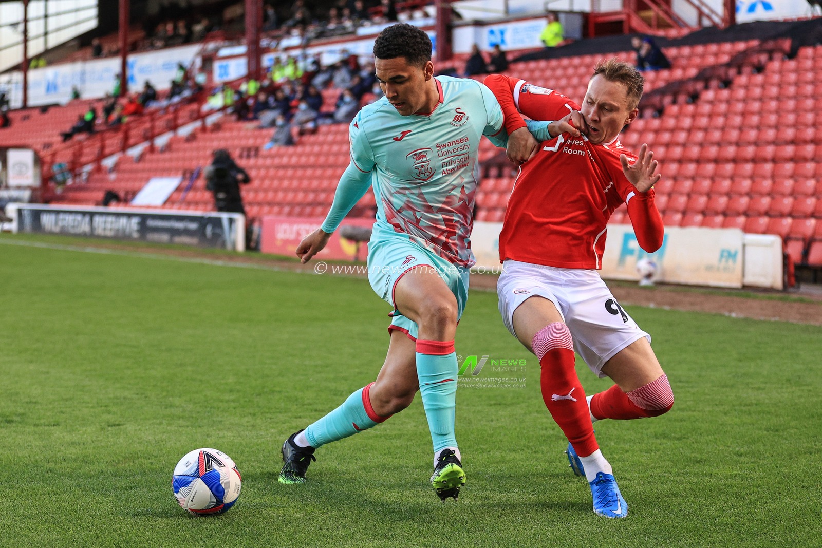 Ben Cabango #44 of Swansea City holds off Cauley Woodrow #9 of Barnsley