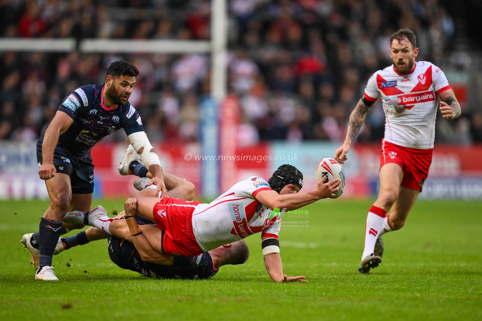 Jonny Lomax of St. Helens offloads to Daryl Clark of St. Helens despite the tackle of Ash Handley of Leeds Rhinos during the Betfred Super League Round 12 match St Helens vs Leeds Rhinos at Totally Wicked Stadium, St Helens, United Kingdom, 24th May 2024

(Photo by Craig Thomas/News Images)