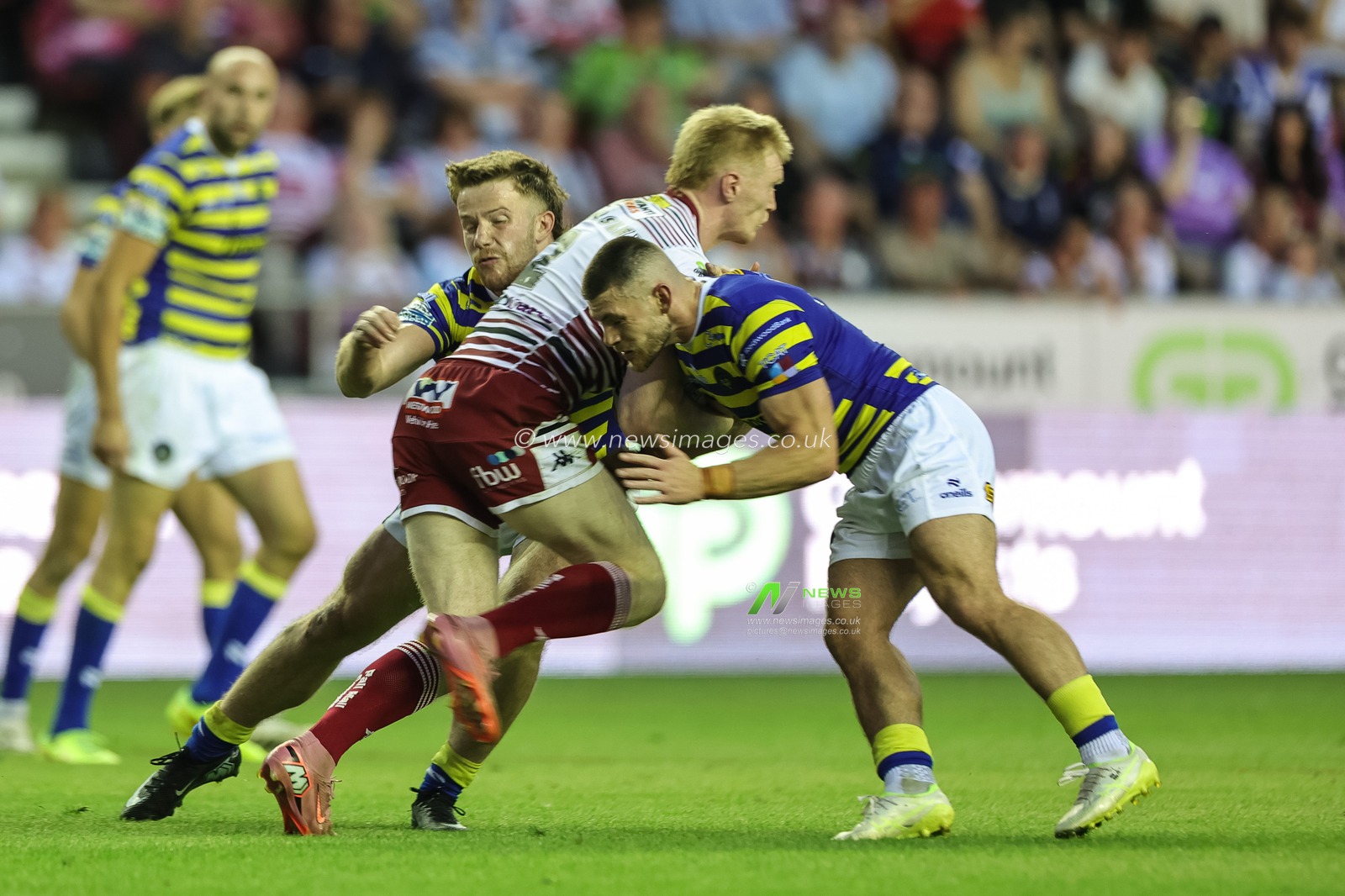 Zach Eckersley of Wigan Warriors is tackled by Danny Walker of Warrington Wolves and Luke Thomas of Warrington Wolves during the Betfred Super League round 18 match Wigan Warriors vs Warrington Wolves at The Brick Community Stadium, Wigan, United Kingdom on 10 July 2026

(Photo by Mark Cosgrove/News Images)