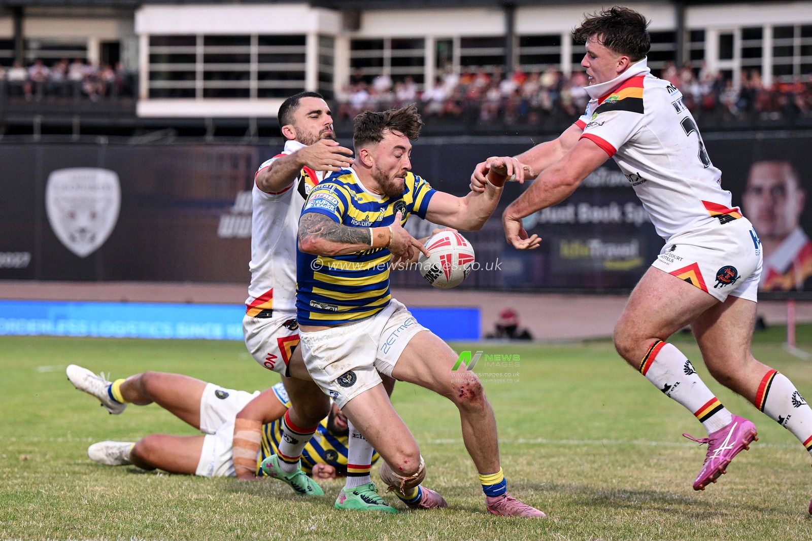 Matty Ashton of Warrington Wolves is challenged by Connor Wynne and Caleb Aekins of Bradford Bulls during the Betfred Super League round 22 match Bradford Bulls vs Warrington Wolves at Odsal Stadium, Bradford, United Kingdom on 08 August 2026

(Photo by Ben Roberts/News Images)