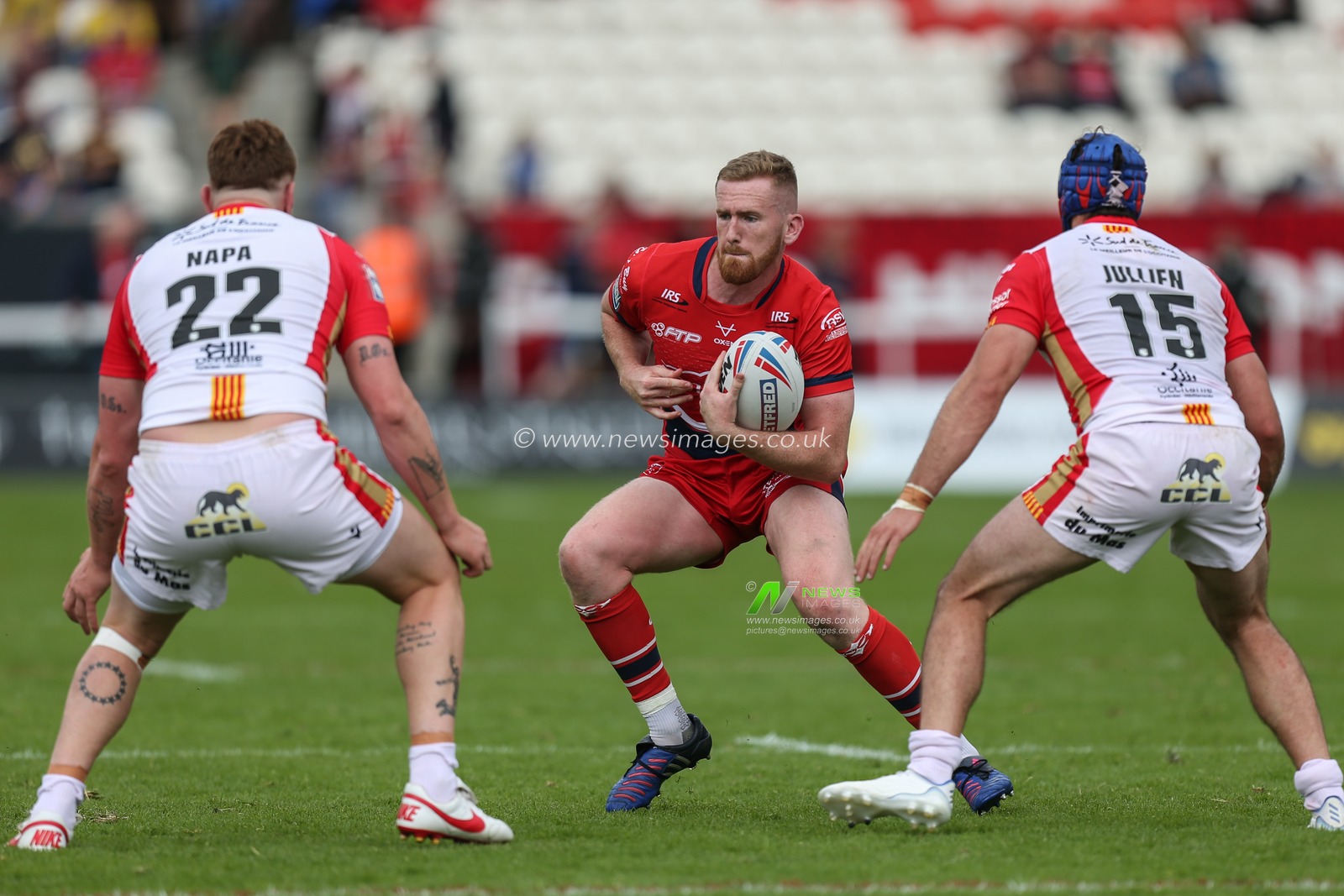 Rowan Milnes #21 of Hull KR runs at Dylan Napa #22 and Benjamin Jullien #15 of Catalans Dragons