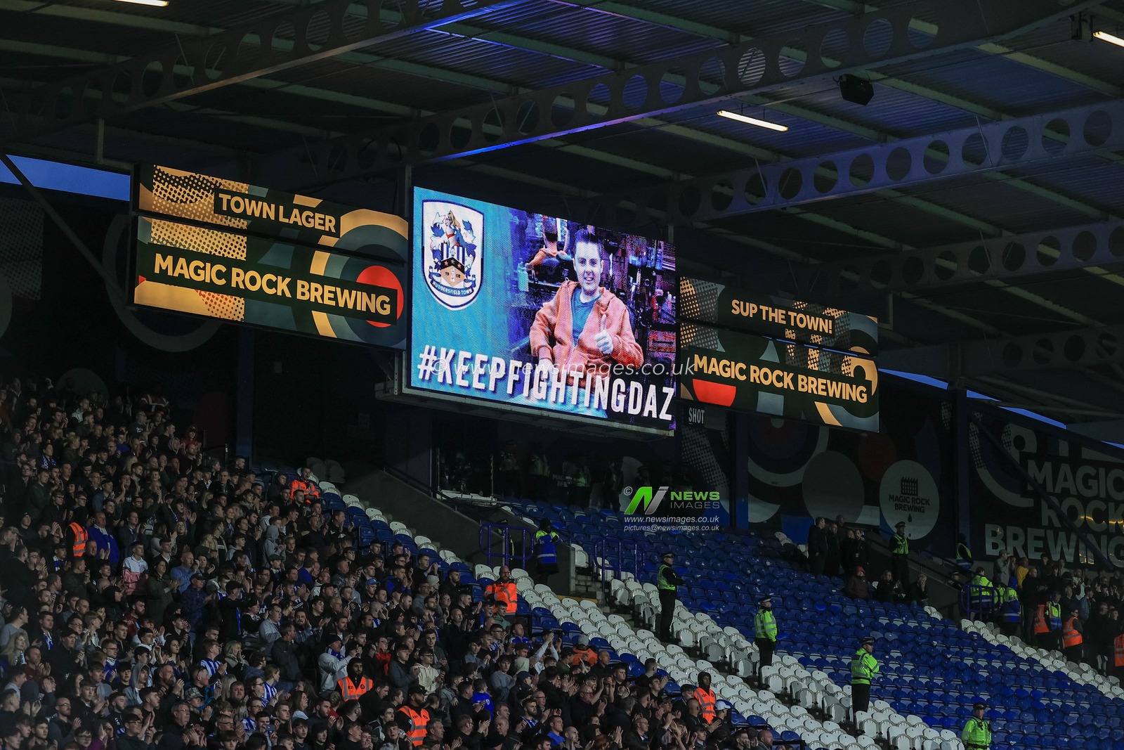 The whole ground applauds the big screen as a message #KEEPFIGHTINGDAZ is displayed