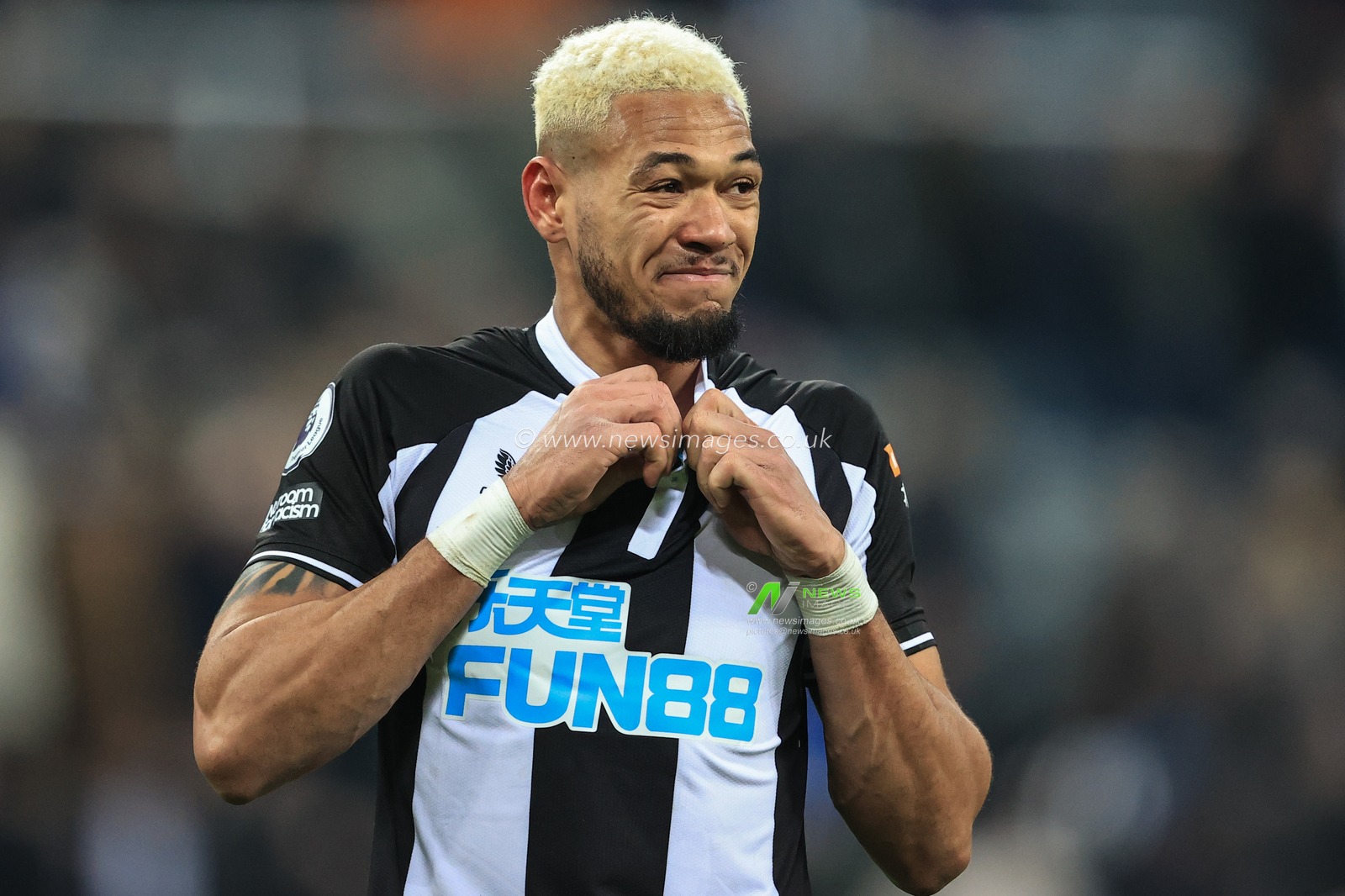 Joelinton #7 of Newcastle United unfastens his shirt as he prepares to give it to a young fan