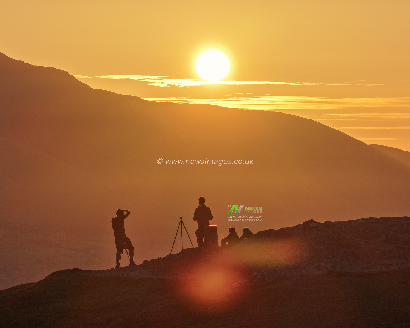 Photographers take pictures as the sun rises from the summit of Catbells overlooking Derwent Water and the town of Keswick In the Lake District, Cumbria, United Kingdom, 19th June 2025.

(Photo by Mark Cosgrove/News Images)