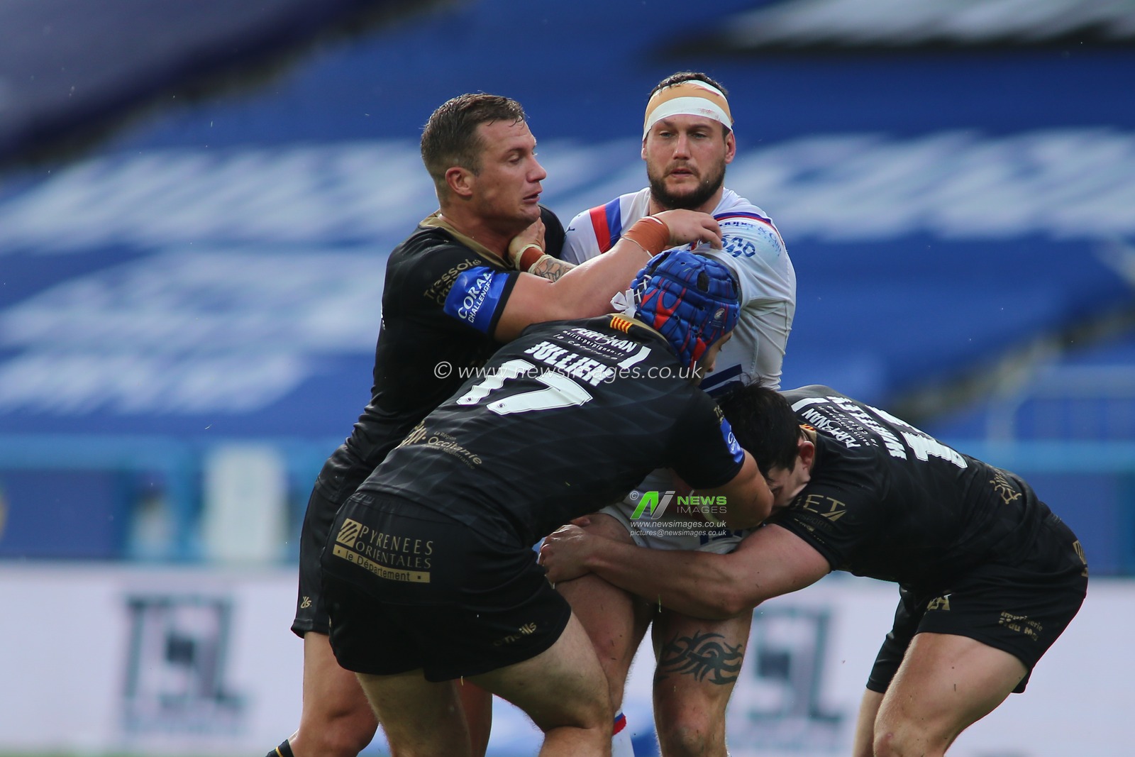 Jay Pitts (14) of Wakefield Trinity tackled by Josh Drinkwater (7), Benjamin Jullien(17) and Matt Whitley (11) of Catalan Dragons.