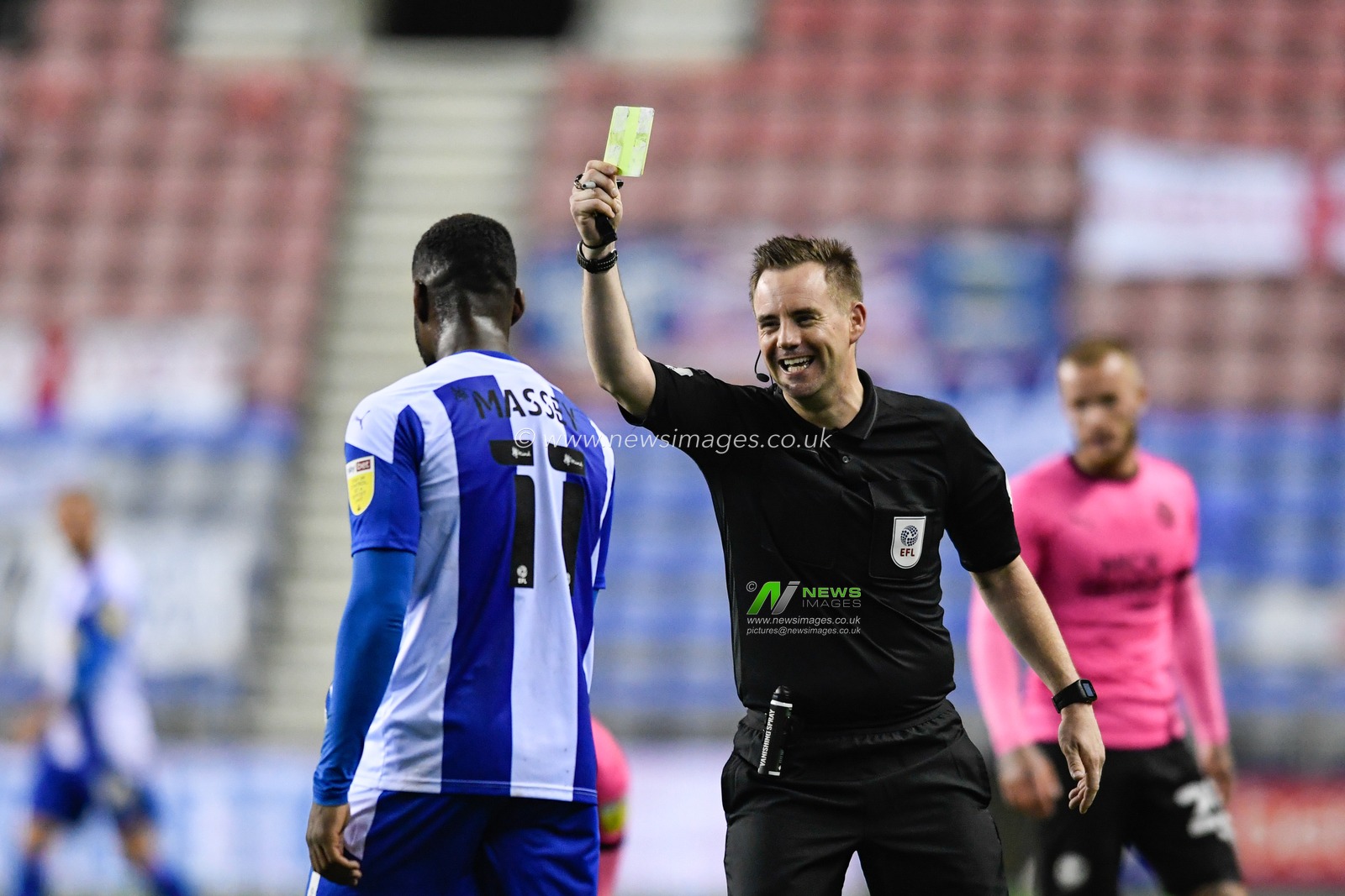 Referee, Ross Joyce smiles as he shows Gavin Massey (11) of Wigan Athletic a yellow card