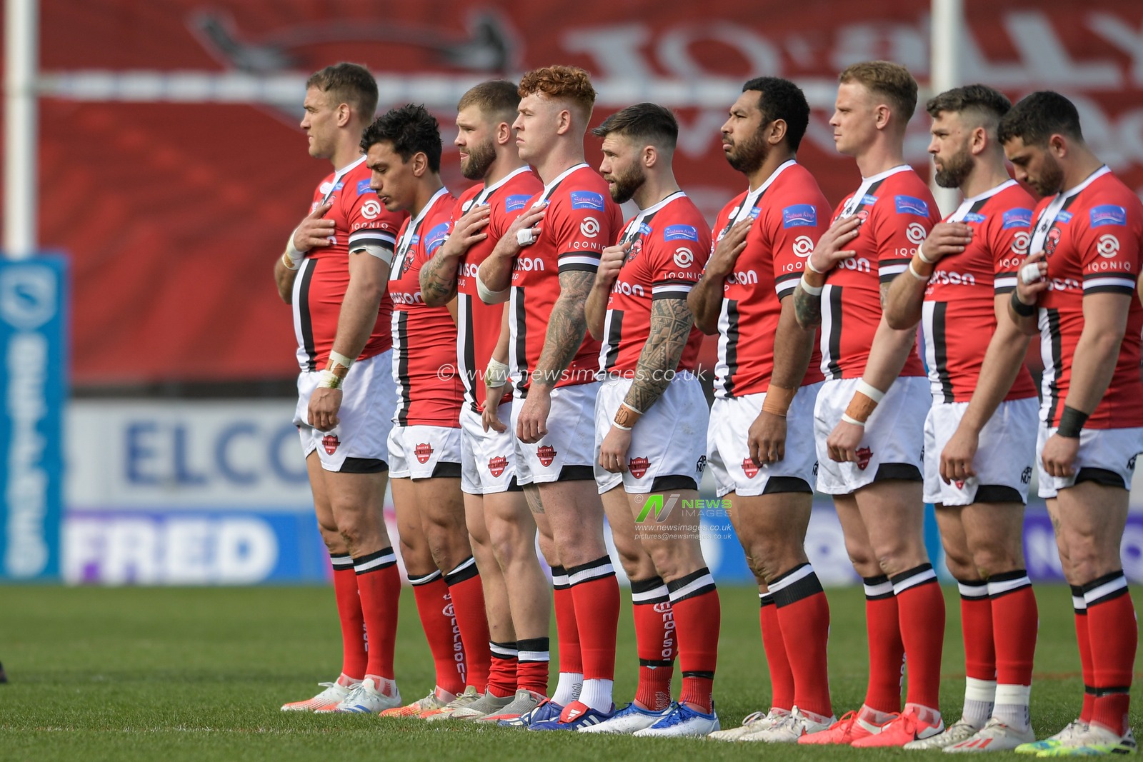 The Salford Red Devils team line up before the game with their hand on their hearts