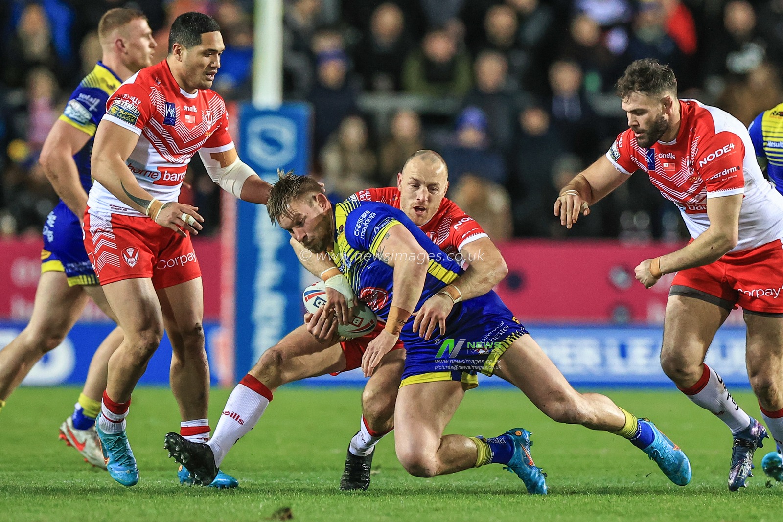 Mike Cooper #10 of Warrington Wolves is tackled by James Roby #9 of St Helens