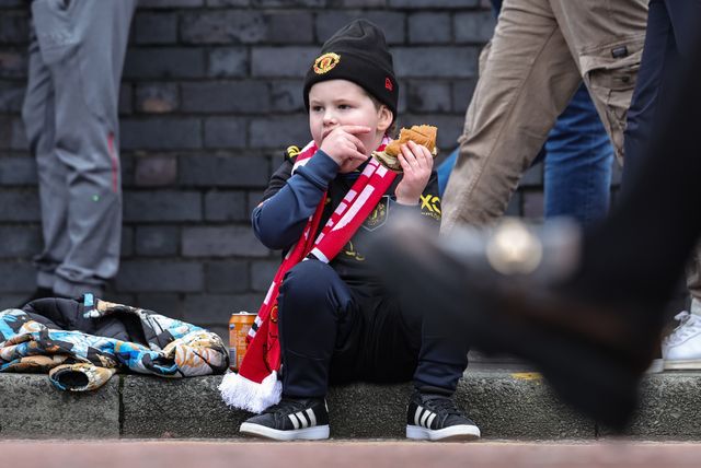 A young Manchester United fans sits in the road curb as he grabs a bite to eat during the Premier League match Manchester United vs Crystal Palace at Old Trafford, Manchester, United Kingdom on 01 March 2026

(Photo by Mark Cosgrove/News Images)