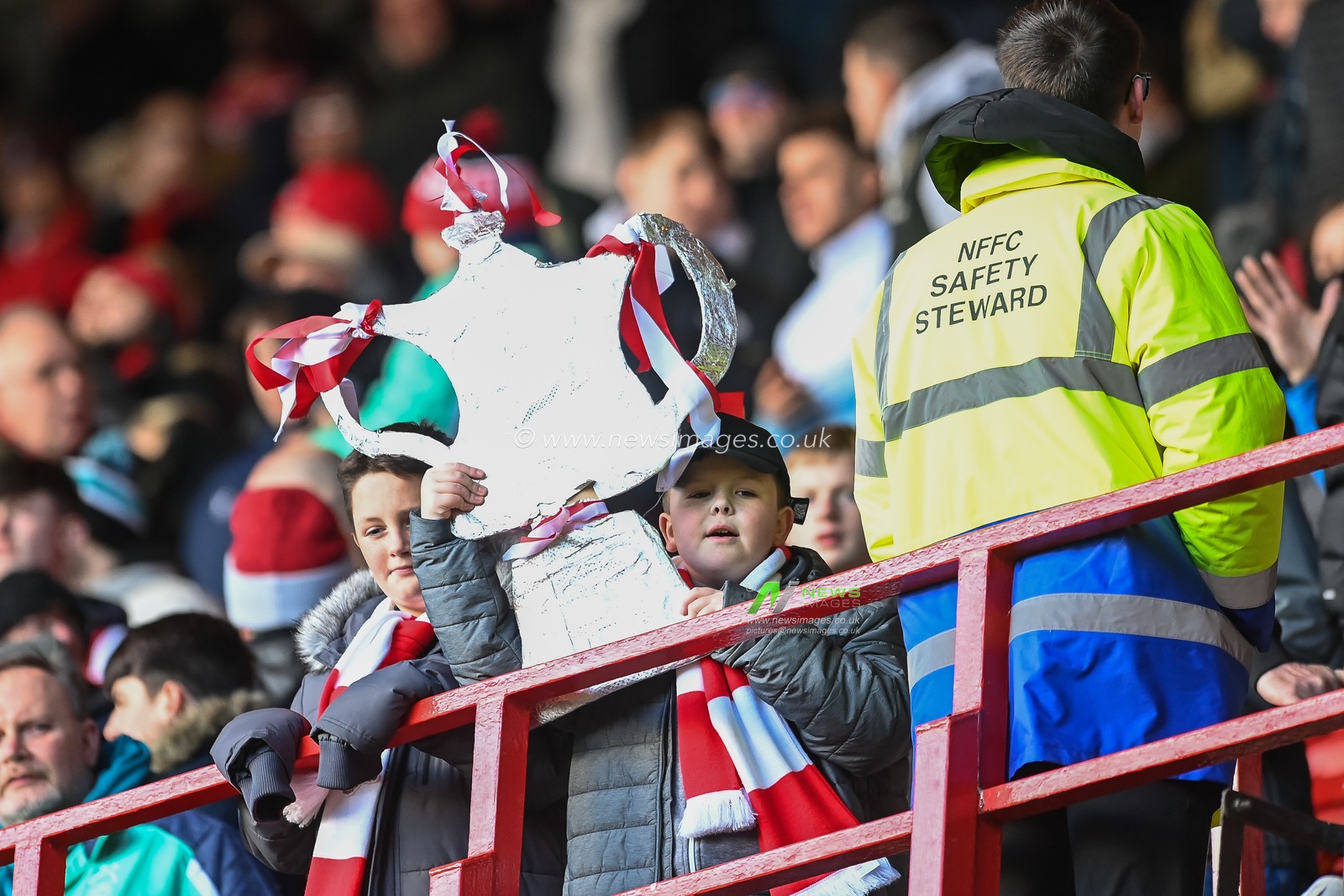 A young fan holds afoot a sliver foil F A Cup ahead of todays game
