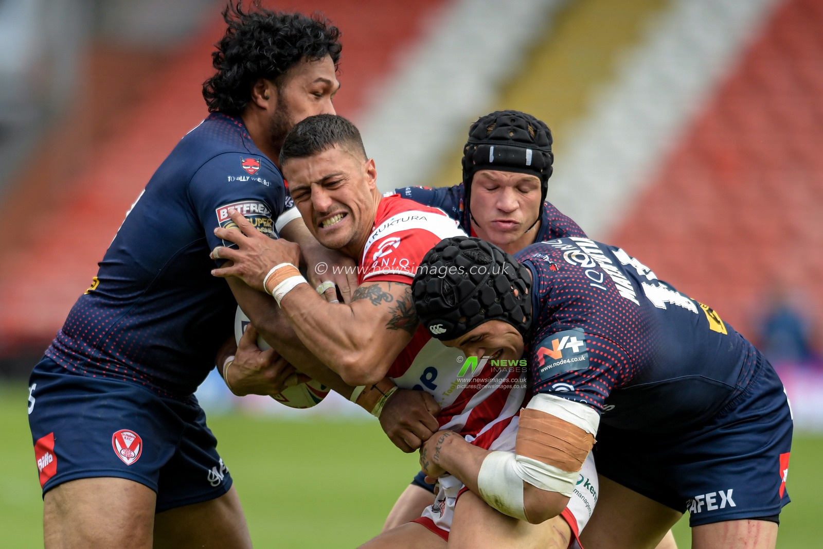 Anthony Gelling (32) of Leigh Centurions is tackled by Jonny Lomax (6), Sione Mata'utia (14) and Agnatius Paasi (17) of St Helens
