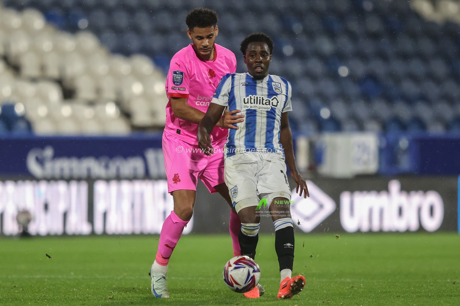 Jaheim Headley of Huddersfield Town passes the ball under pressure from Kyran Lofthouse of Barnsley during the Bristol Street Motors Trophy match Huddersfield Town vs Barnsley at John Smith's Stadium, Huddersfield, United Kingdom, 8th October 2024

(Photo by Alfie Cosgrove/News Images)